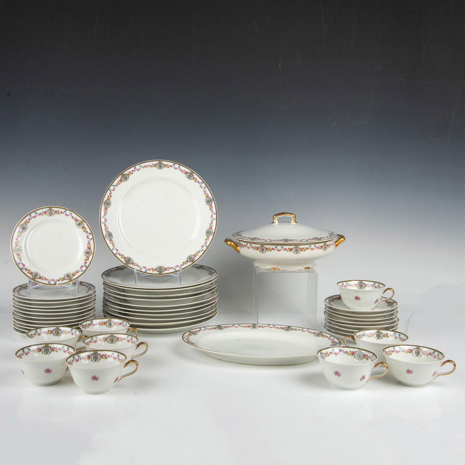 31pc Antique Charles Ahrenfeldt Limoges Porcelain Serveware: This fine porcelain set features a delicate pattern of flowers beautifully adorning the, enhanced by gold details. Includes: 9 Cups, 8 Saucers, 12 Bread and butter plates, 11 Dinner plates, 1 Covered