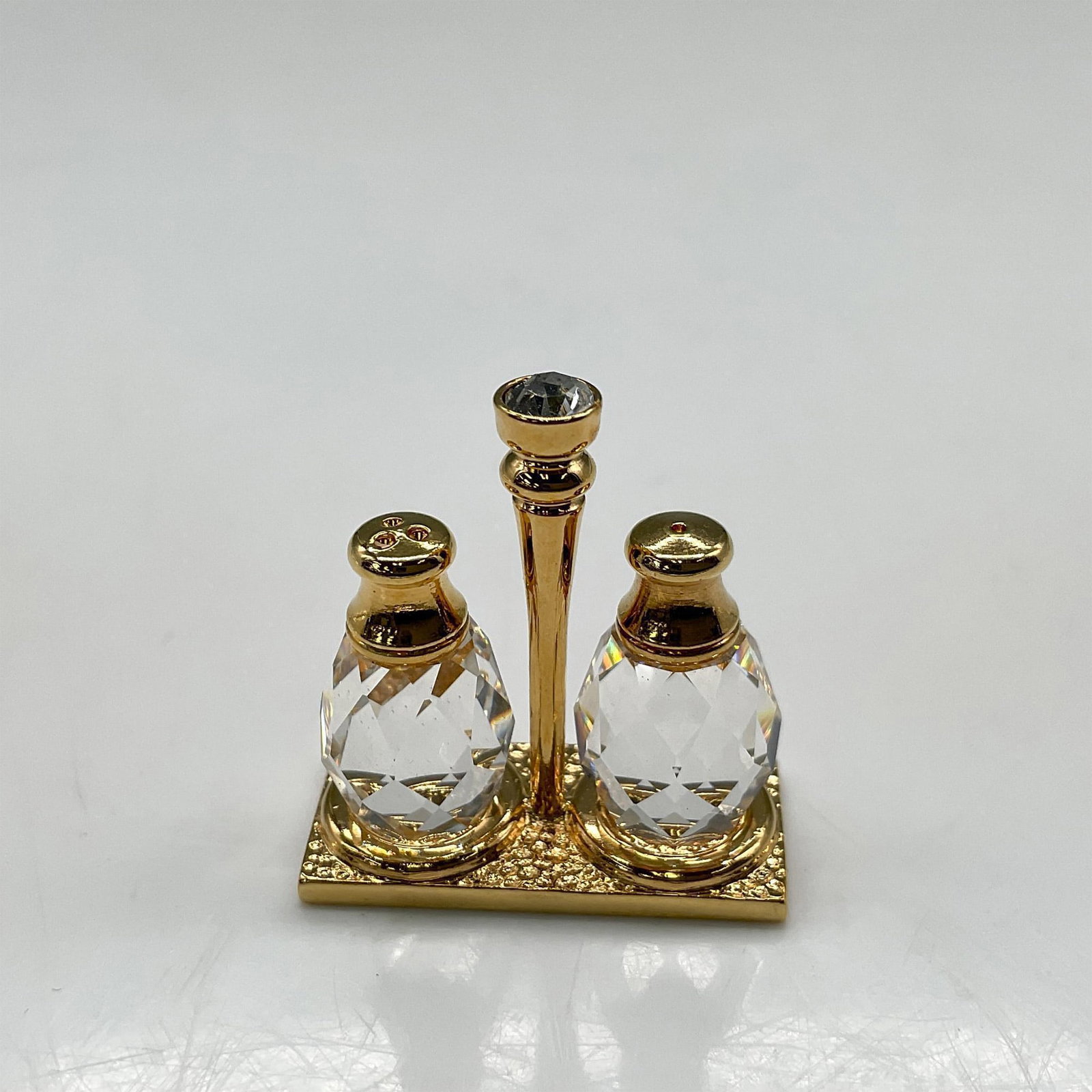 Swarovski Crystal Memories, Salt and Pepper Shakers Gold: Gold plated miniature cruet set with crystal shakers. Swarovski impressed mark. This item has its original box: 2"L x 3.5"W x 1.25"H. Artist: Anton Poppinger Issued: 1993 - 1996 Dimensions: 1"W x 1.25