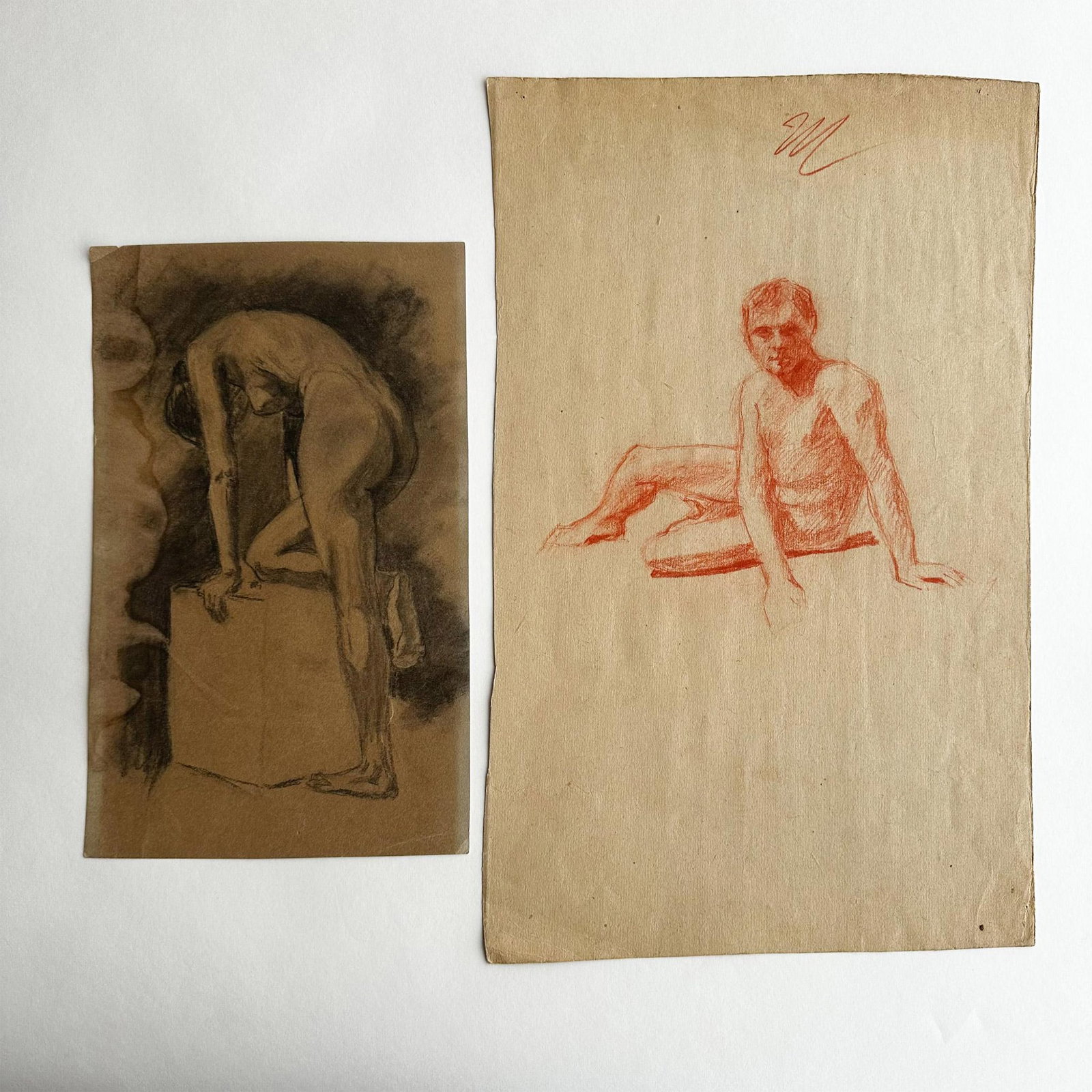 2 Original Nudes Pastel & Sanguine Drawings on Paper: Set of two original pastel and sanguine nude studies on beige laid paper. One drawing depicts a seated nude male and the second a standing nude female resting one leg on a base. Male nude drawing dime