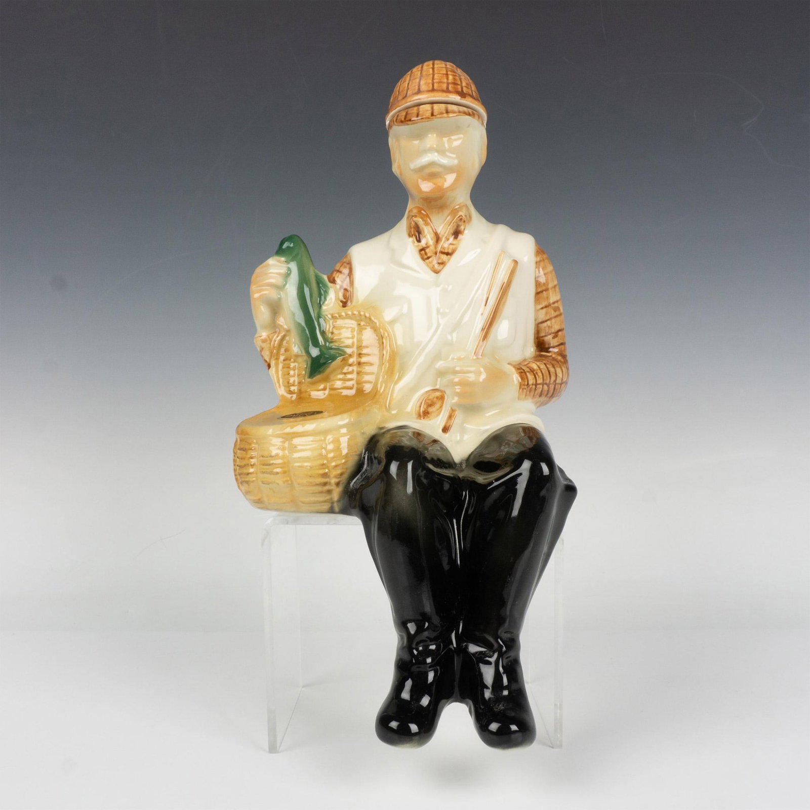 Ballantines Scottish Fisherman Decanter: A fisherman in a crisp white vest and sturdy black boots delicately transfers his catch into a waiting basket. Ballentine backstamp. Issued: 1969 Dimensions: 7.25"L x 6.5"W x 13.5"H