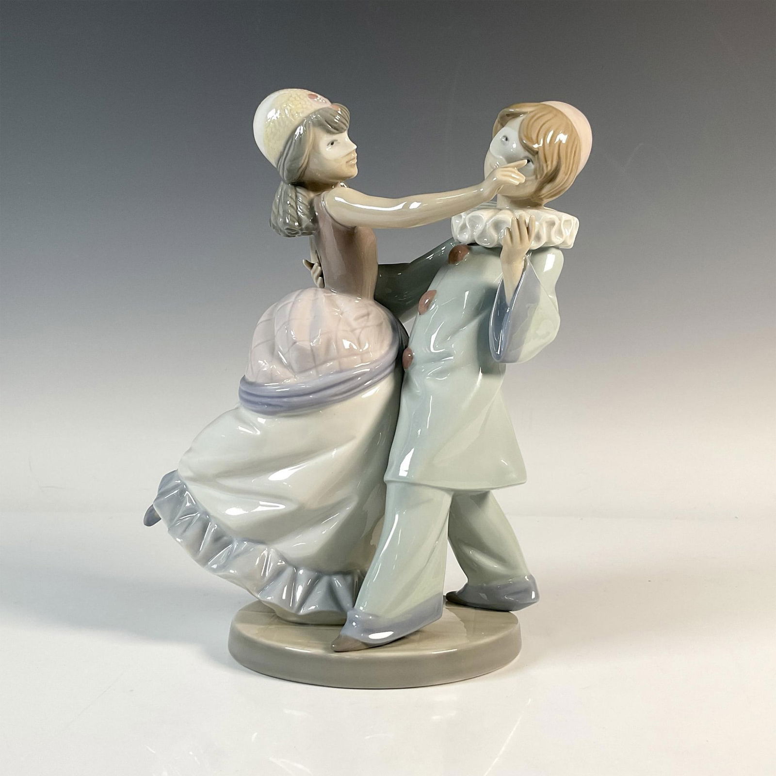 Masquerade Ball 1005452 - Lladro Porcelain Figurine: A glossy figure of a young couple in clown attire and formal dress, joyfully dancing together while adorned with masks. Lladro backstamp. Artist: Francisco Catala Issued: 1988-1993 Dimensions: 7.5"L x