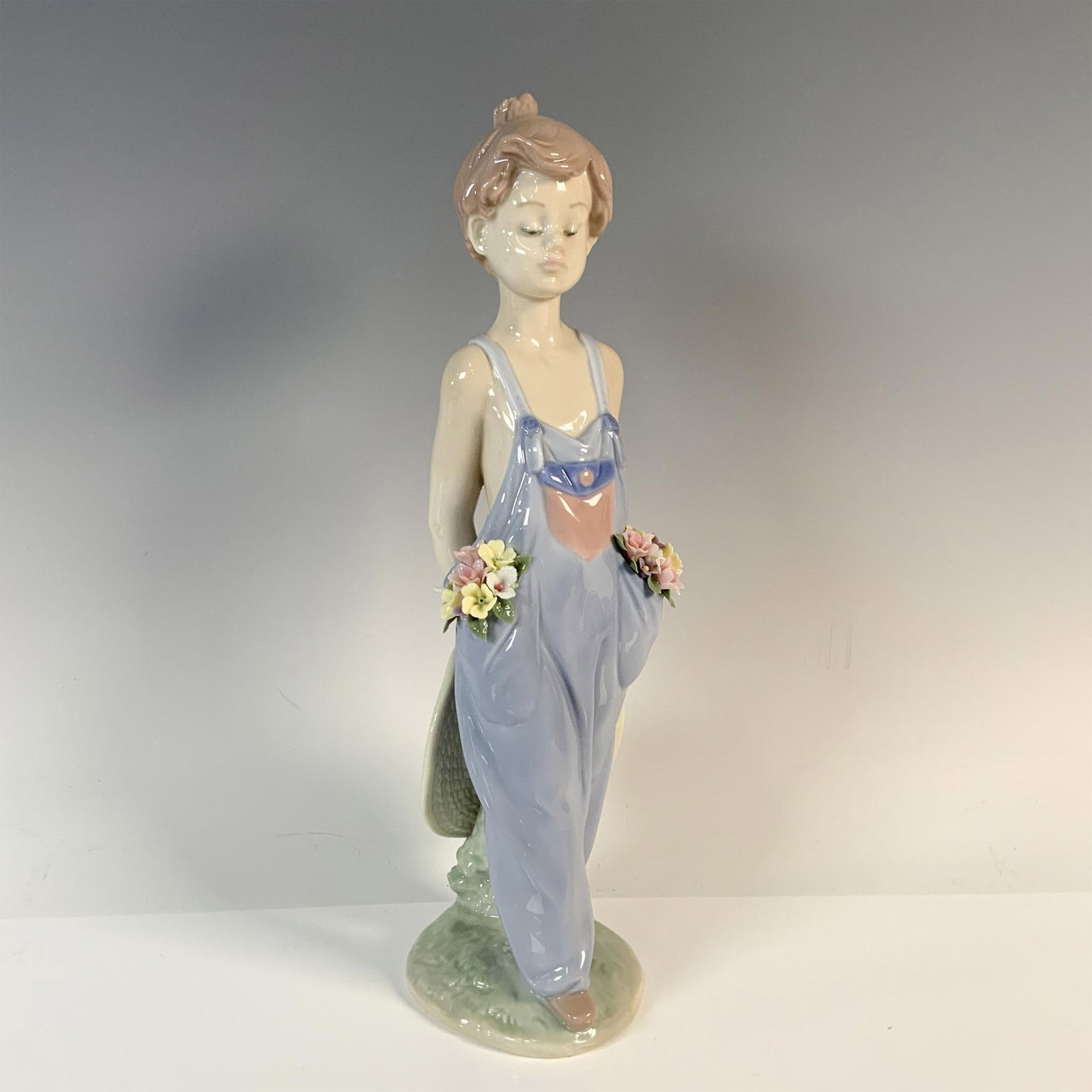 Pocket Full Of Wishes 1007650 - Lladro Porcelain Figurine: Modeled in pale blue colors with detailed colorful flowers. Lladro backstamp. Includes the original box, dimensions: 5.5''L x 6.75''W x 12''H. Artist: Antonio Ramos Issued: 1997 Dimensions: 3.25''L x 