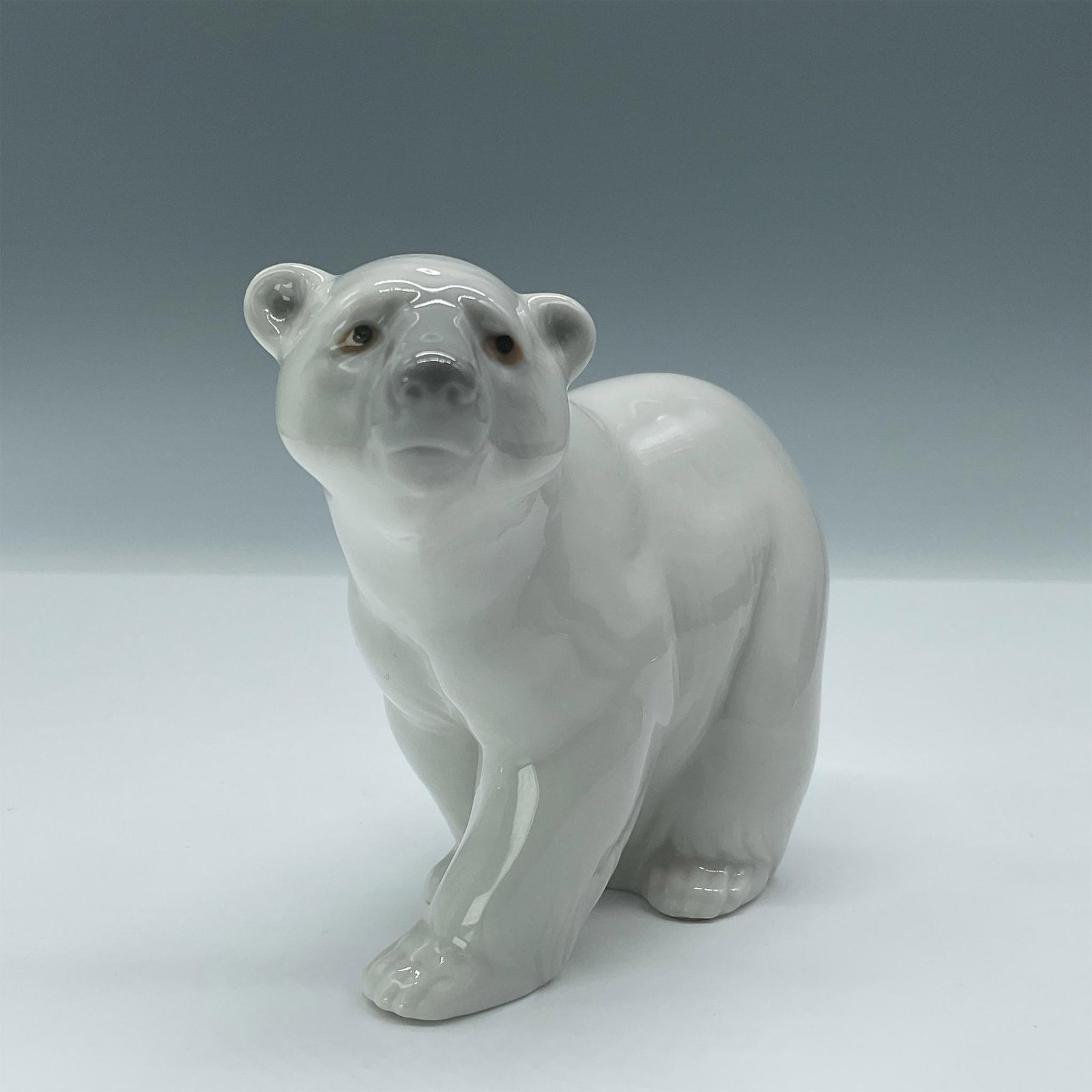 Attentive Polar Bear 10011207 - Lladro Porcelain Figurine: Glazed figural of white bear with gray face and inset eyes. Lladro backstamp. Artist: Juan Huerta Issued: 1972-2021 Dimensions: 5"L x 2.5"W x 4"H Manufacturer: Lladro Country of Origin: Spain