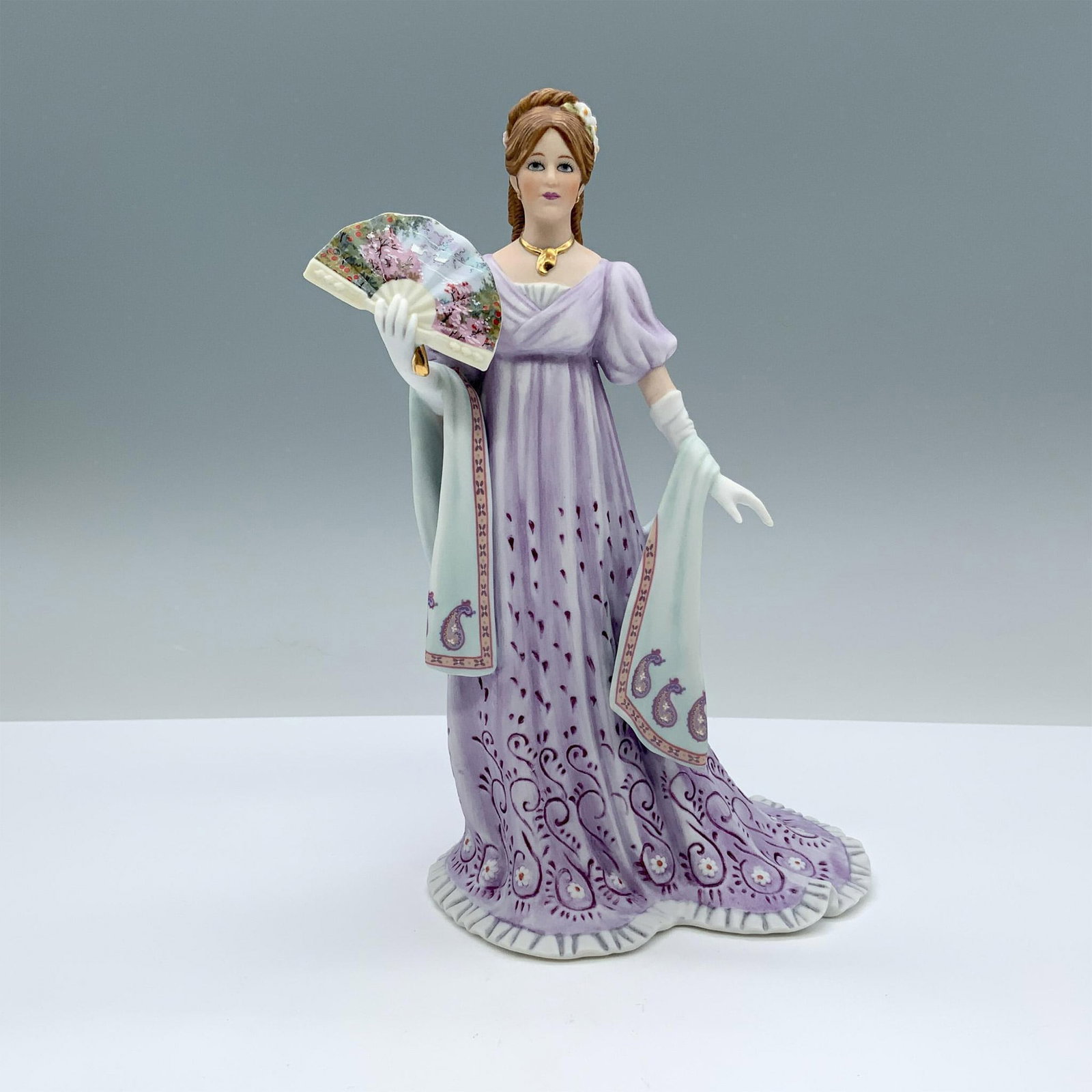 Lenox American Fashion Figurine, Gala At The White House: Matte porcelain lady figurine featuring lavender coloration with finely painted floral detail and gilt highlights. Lenox backstamp on the bottom. Issued: 1987 Dimensions: 5"L x 4"W x 8.5"H Manufacture