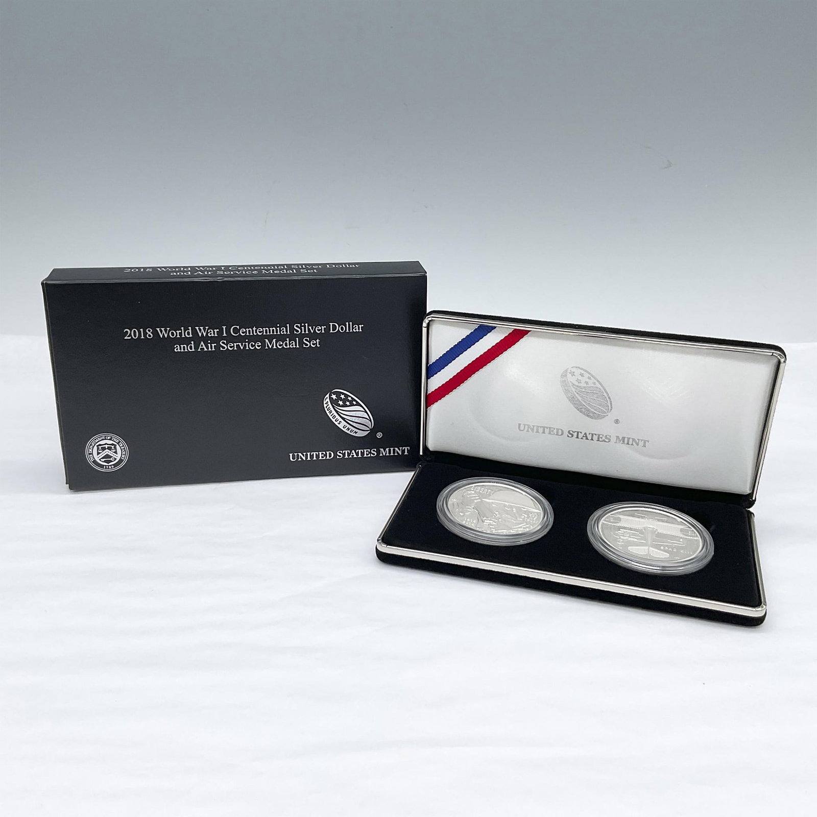 2018-P & D WWI Centennial Silver Dollar & Air Service Medal: Philadelphia Mint World War I Centennial Proof Silver Dollar; the obverse side depicts a soldier holding a rifle, barbed wire twine near the bottom. The reverse side features stylized poppies mixed wi