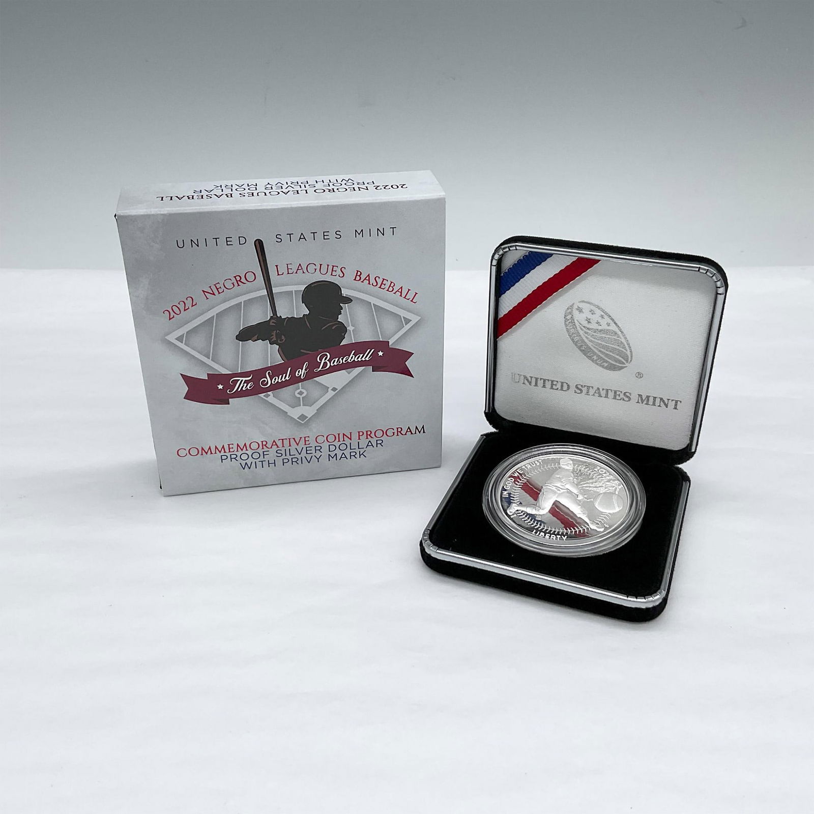 2022 Negro Leagues Baseball Proof Silver Dollar: Commemorative coin with privy mark. The obverse side depicts a pitcher in mid-throw, the ball in the foreground and baseball stitching as the border. The reverse side depicts a player's point of view