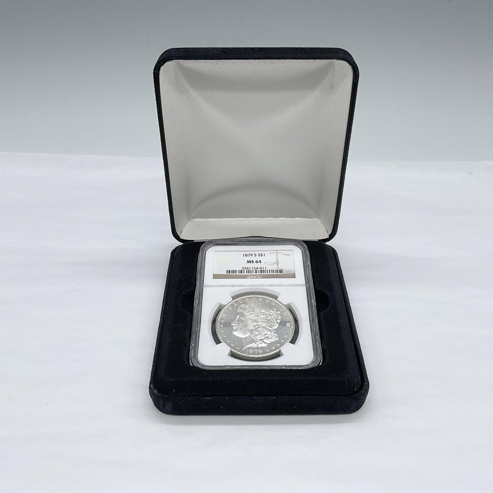 1879-S Morgan Silver Dollar NGC MS64: Slabbed and Graded MS64. The obverse design depicts the profile of Liberty in a cap with a small floral crown. The reverse design is a bald eagle clutching arrows and a branch. The coin is in a protec