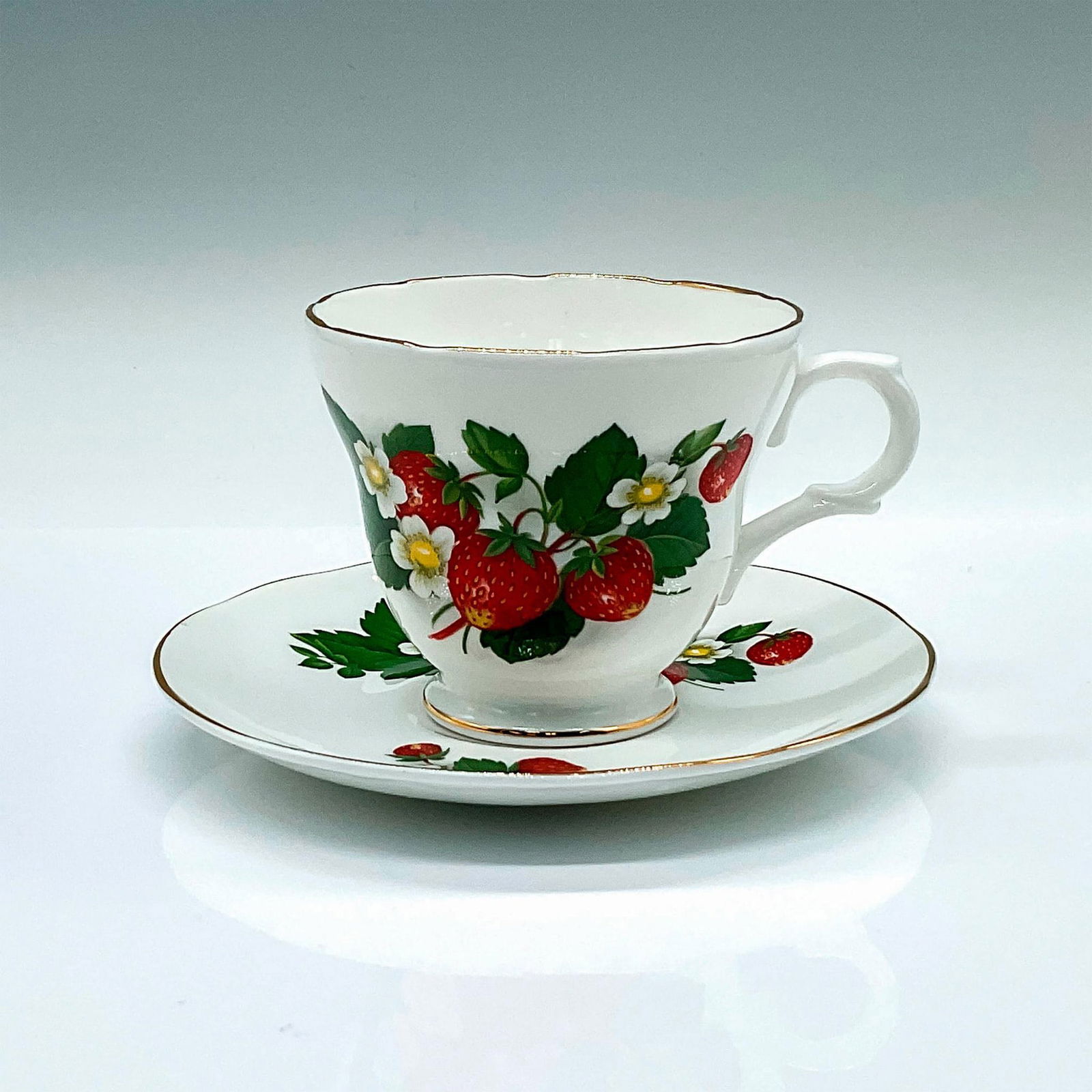 2pc Crown Trent Fine Bone China Strawberry Cup and Saucer: A vintage white tea cup and saucer set with gold trims. Decorated in a strawberry decor. Crown Trent backstamps. Cup: 4.25"L x 3.5"W x 3"H. Saucer: 5.5"W x 0.75"H. Manufacturer: Crown Trent Country of