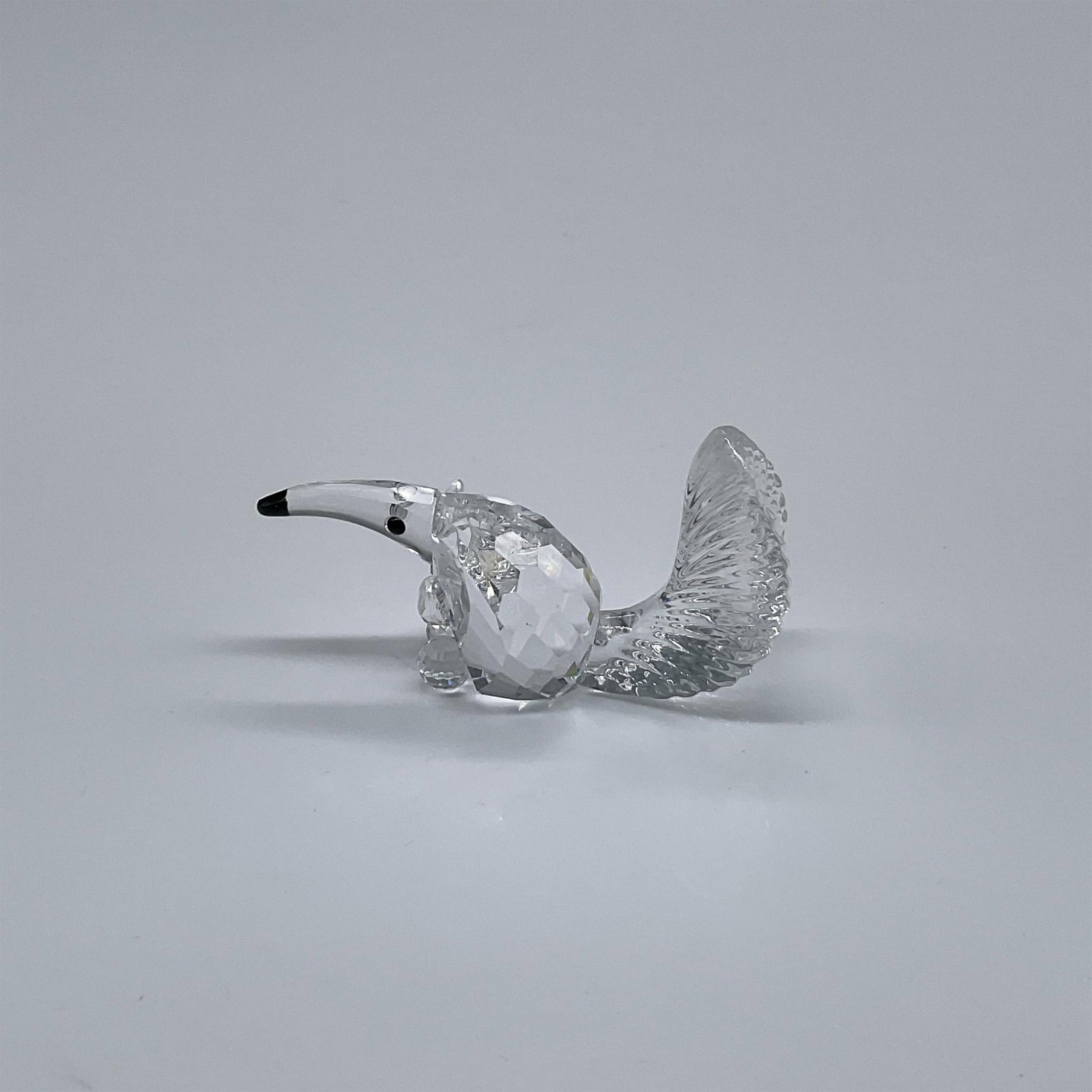 Swarovski Crystal Figurine, Anteater: Part of the Endangered Species collection. A seated anteater made from clear crystal with black eyes and nose. Swarovski swan mark. This item has its original box: 3.25"W x 2.5"H. Artist: Adi Stocker 