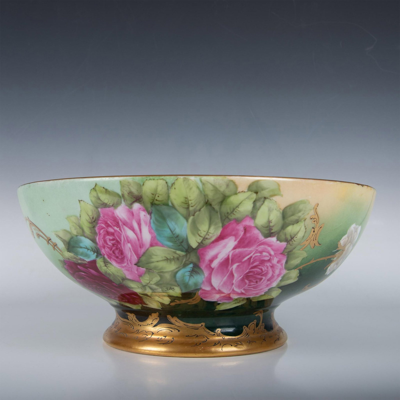 T & V Limoges Porcelain Hand Painted Punch Bowl: Gilt edge bowl hand painted with roses, vines and leaves. Colored in green, pink and faded cream. Gilt design on base. T&V backstamp. Issued: 20th century Dimensions: 6.25"H x 14.5" dia. Manufacturer: