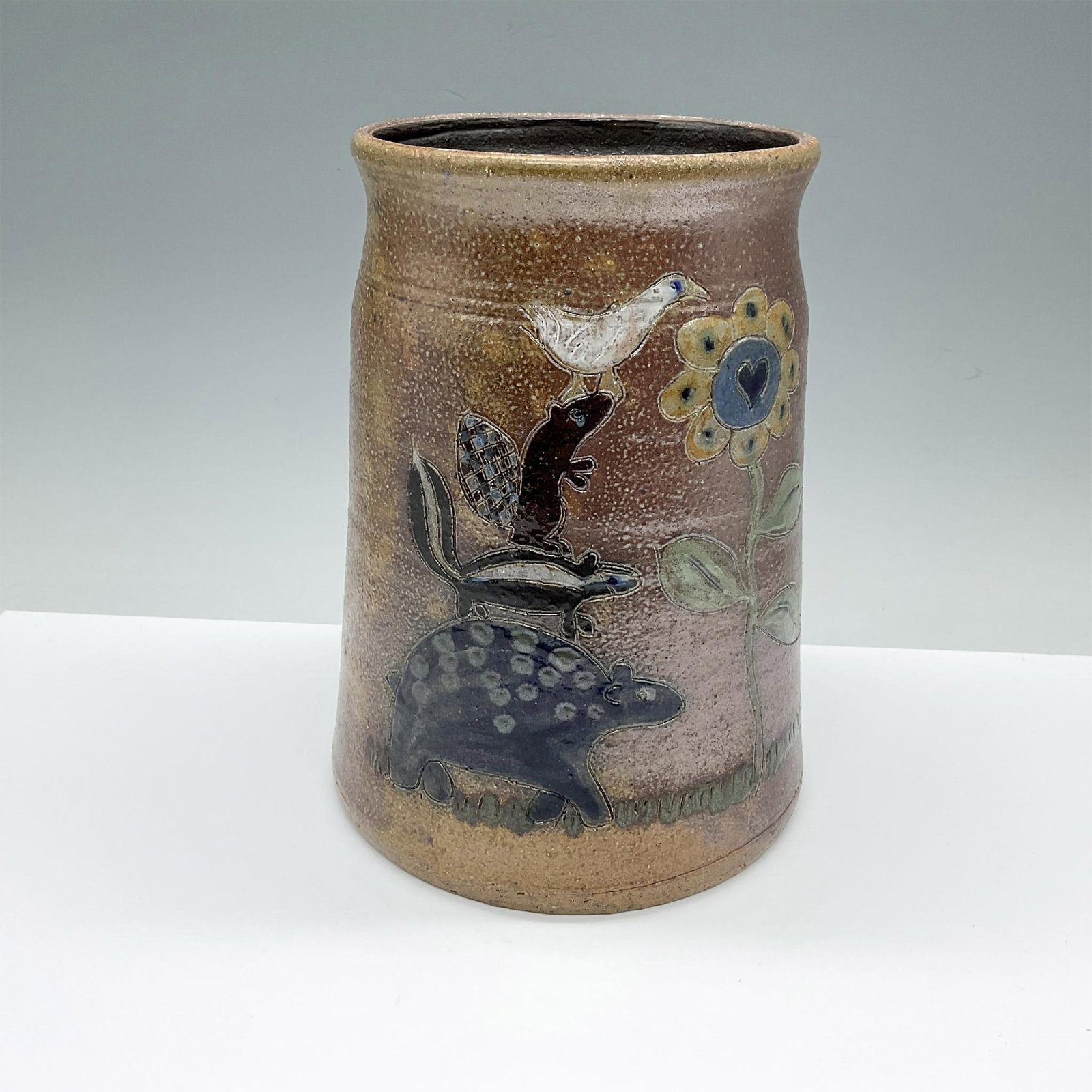 Vintage Stoneware Salt Glazed Folk Art Vase Signed: A semi-cylindrical brown glazed base with salt speckles. Depicts a delightful incised scene of four animals, stacked on top of one another, to reach the top f the tall sunflower. Artist carved signatu