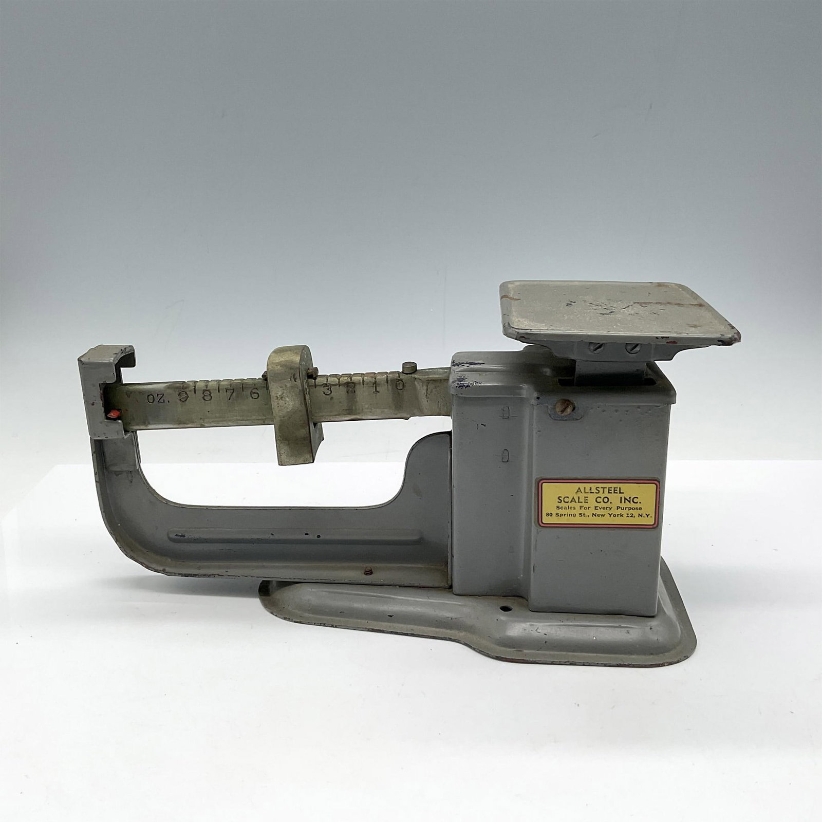 Vintage Triner Steel Mfg. Scale: Gray metal scale with 9 oz. weight capacity. Screw at end of arm to rebalance scale. Allsteel Co. mark and Triner Steel impressed mark. Issued: 20th century Dimensions: 9"L x 4"W x 5"H Manufacturer: T