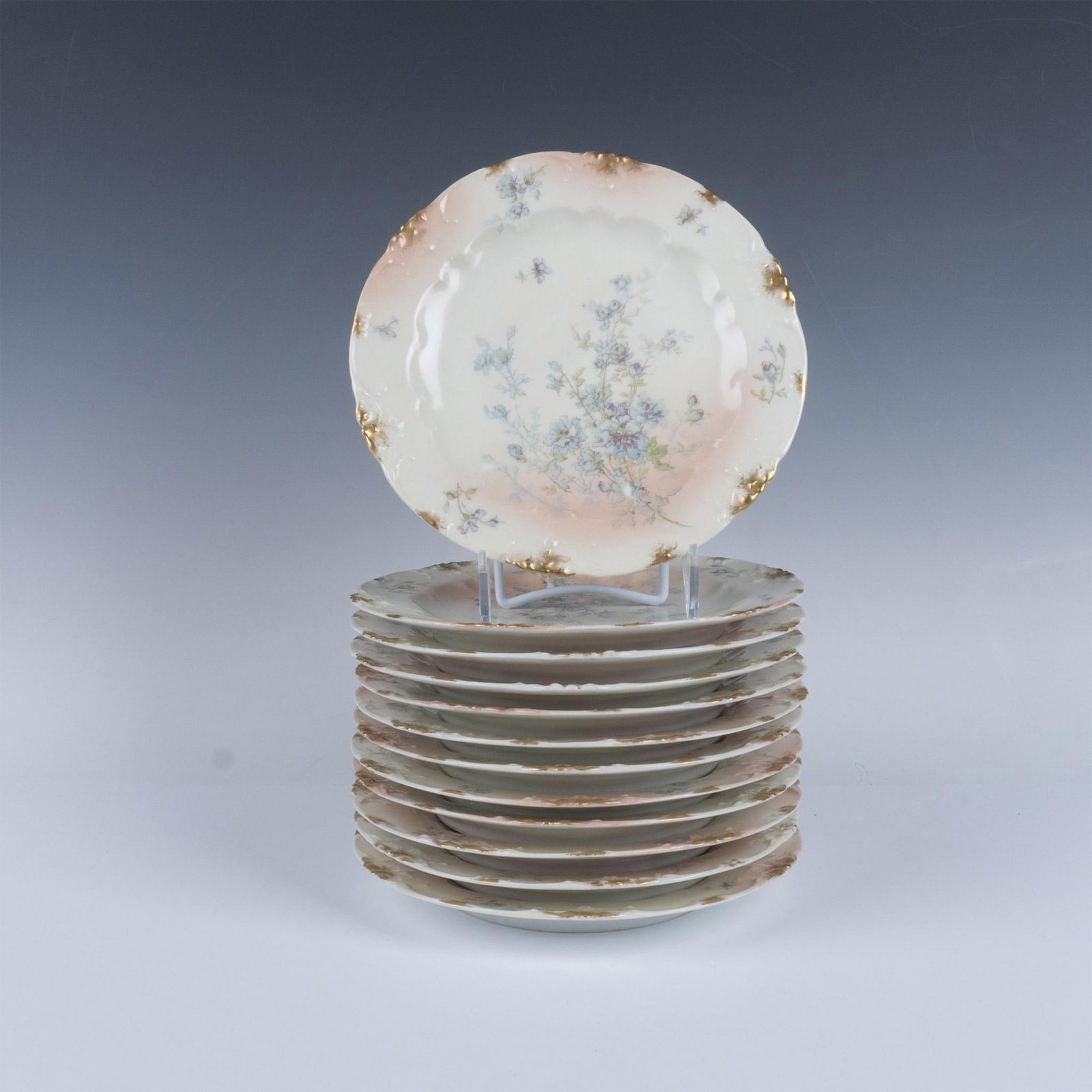 12pc Delinieres Limoges French Porcelain Floral Salad Plates: A pink and cream-colored finish with sprayed gilt trims. Decorated with blue wildflowers. Delinieres Limoges France. Issued: 1895 - 1900 Dimensions: 8.5"W x 1"H Manufacturer: Delinieres Country of Ori