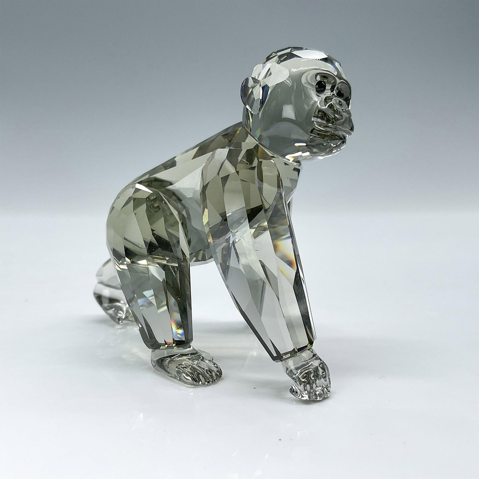 Swarovski Crystal Figurine, SCS Gorilla Cub: This mischievous gorilla cub is made from faceted Black Diamond crystal, with jet crystal eyes. Swarovski backstamp. Item comes with original box measuring 5"L x 5"W x 4"H. Artist: Anton Hirzinger Iss