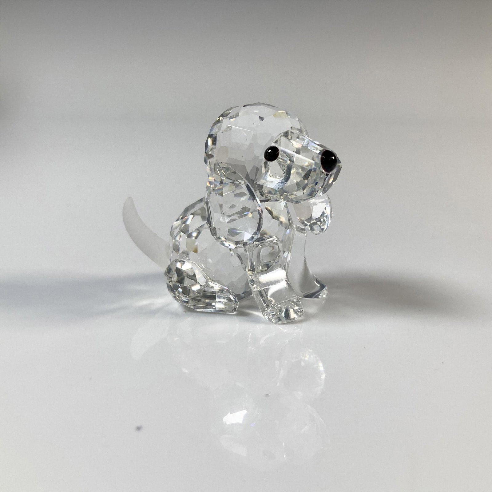 Swarovski Silver Crystal Beagle Figurine, 7619 000 001: Puppy is sitting and has a clear cut crystal body with black eyes and nose. This item has its original box which measures 2.75"H x 2.5" dia. Acid etched Swarovski backstamp. Artist: Adi Stocker Issued