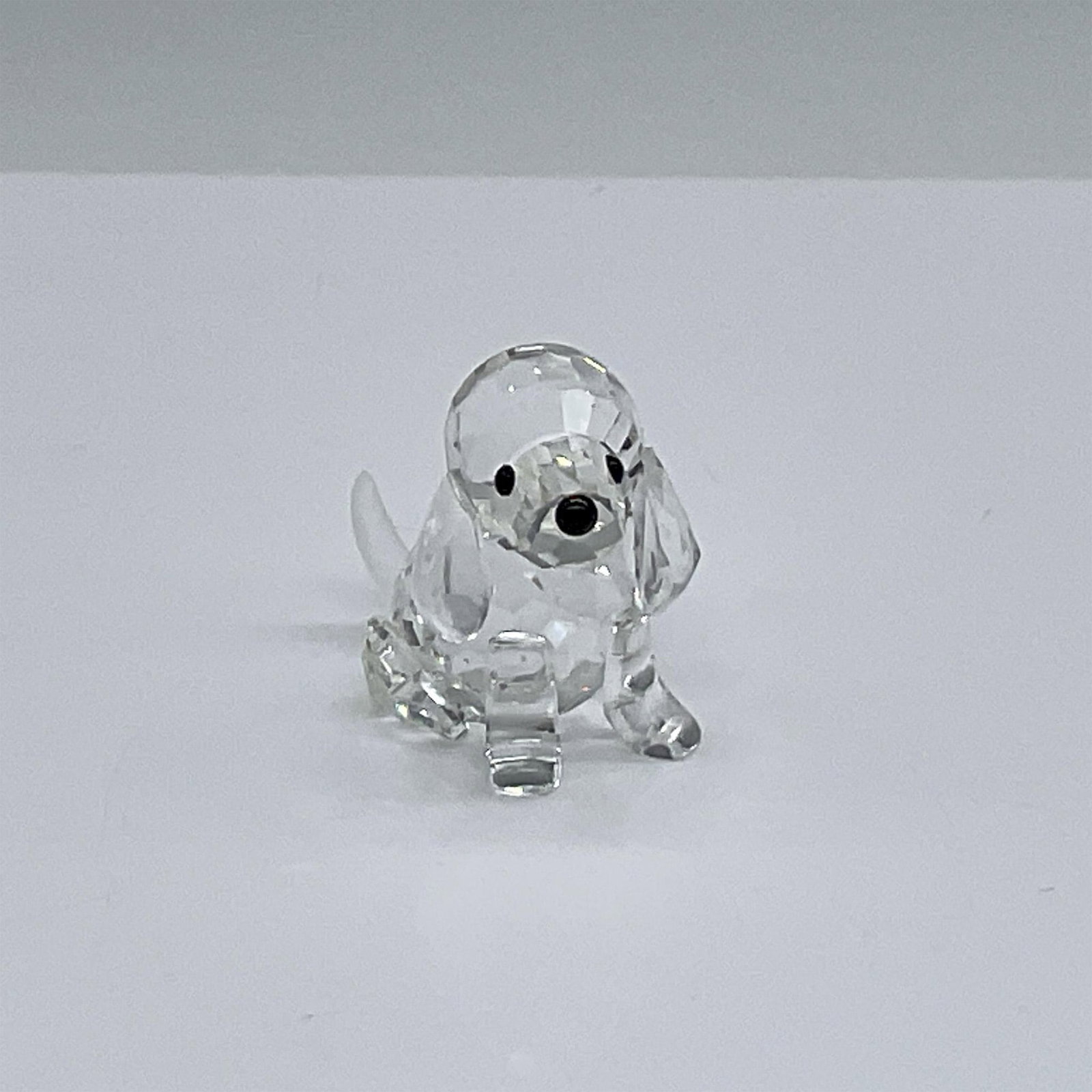 Swarovski Silver Crystal Figurine, Beagle Puppy: Puppy is sitting at attention. It has a clear cut crystal body with black eyes and nose, and a frosted tail. This item has its original box which measures 2.5"H x 3.25" dia. Artist: Adi Stocker Issued