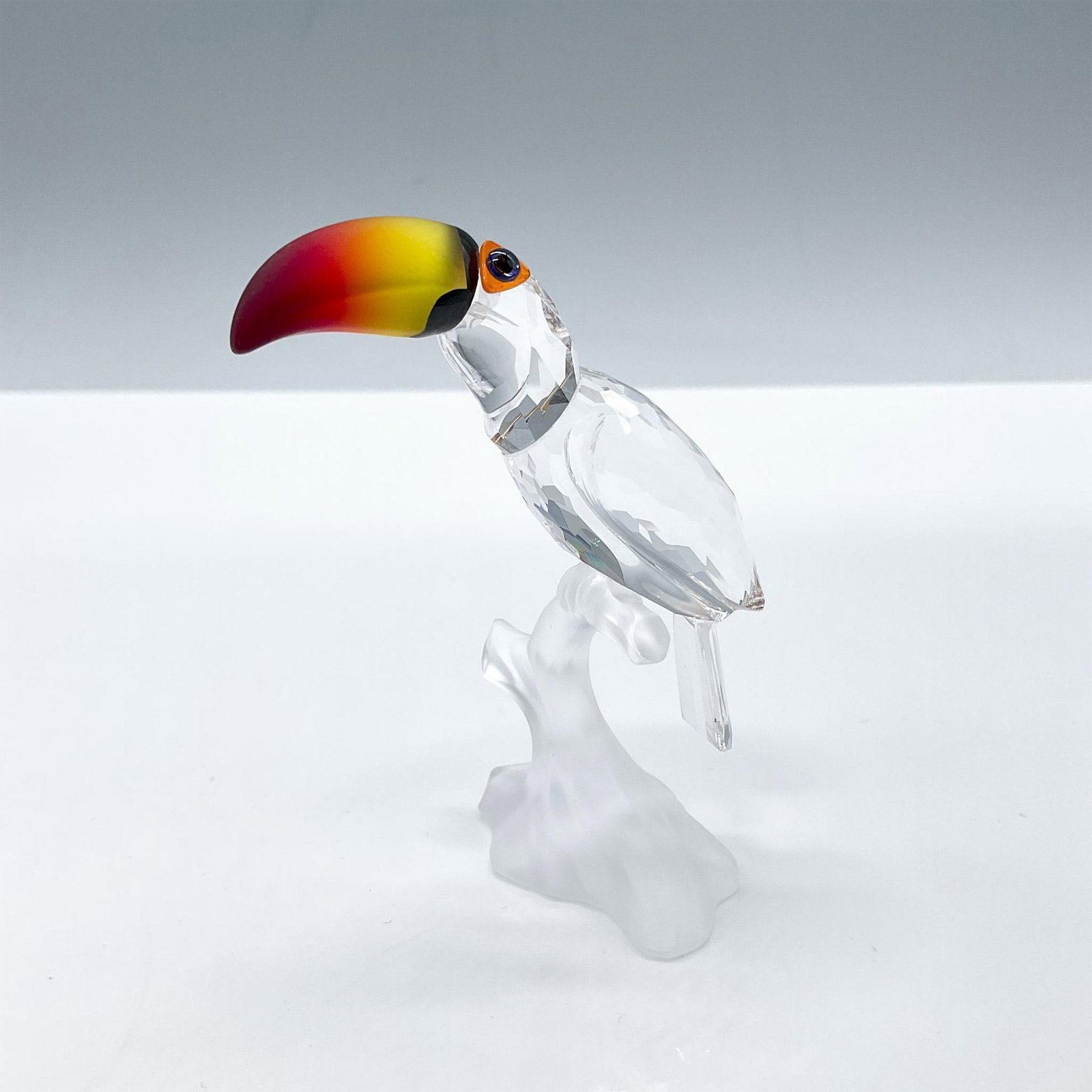 Swarovski Crystal Figurine, Toucan: This crystal toucan was made from clear crystal and sits on a frosted branch. His beak is made from fire opal crystal. The toucan was part of the Feathered Beauties collection. Includes the certificat