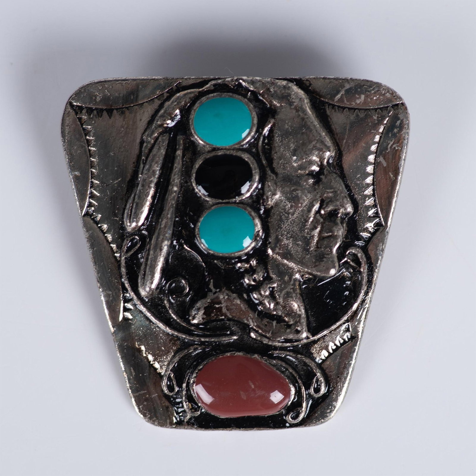 Silver Metal Native American Chief Brooch: Southwestern style silver tone brooch depicting a Native American chief with enameled accents. Dimensions: 2"L x 2"W