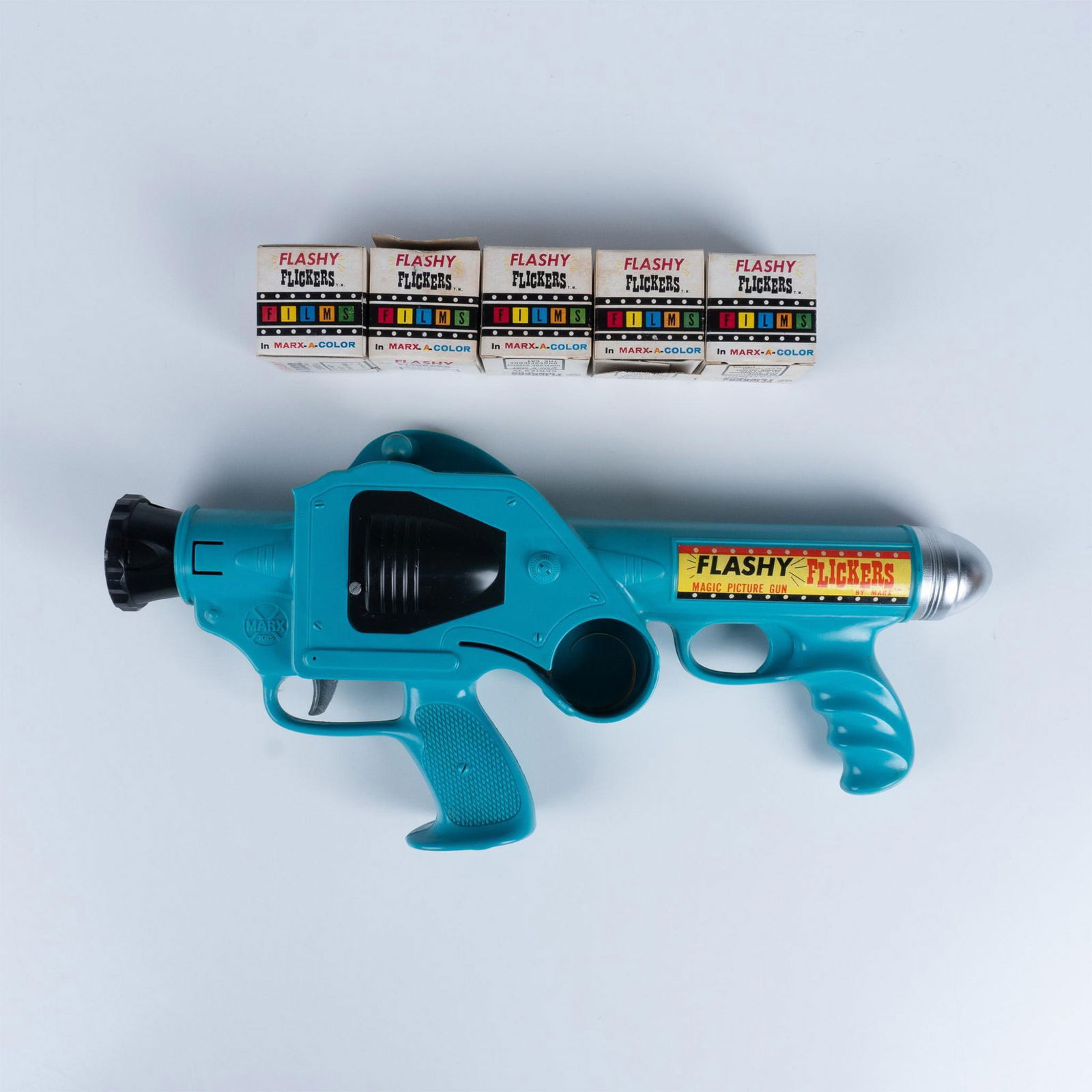 Marx Toys Flashy Flickers Magic Picture Firearm Toy: Vintage 1960s battery powered toy film projector with instruction pamphlet and 5 colored film reels. Reels includes character such as Batman, Green Lantern, Wonder Woman, Hopalong Hoppity, the Phantom