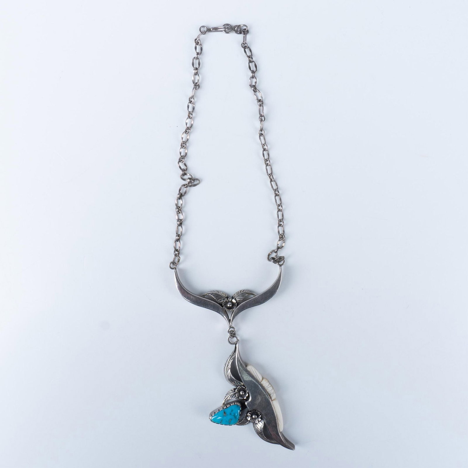 Les Baker Jewelry Sterling Silver & Turquoise Necklace: From the Southwest Jewelry artist, presents this representative gorgeous piece that features a bull resemblance with flowers, completed by a Turquoise stone and ivory inlaid. Total weight: 28g. Marked