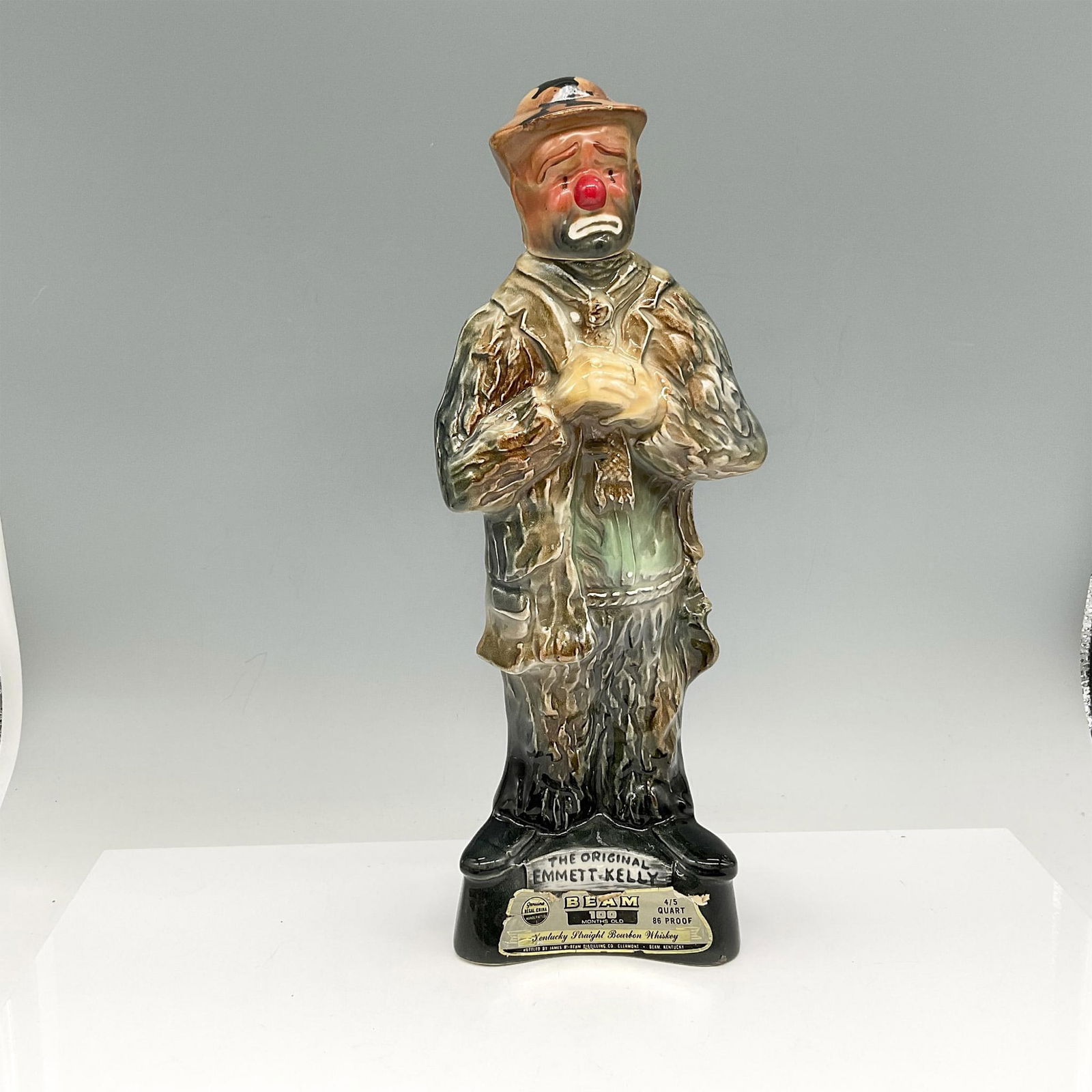 Vintage Jim Beam Porcelain Decanter, Emmett Kelly: Jim Beam gives a nod to this famous clown. Glossy figure is colored in brown, green and red standing on black base displaying his name. Jim Beam and Regal China embossed mark. Issued: 1973 Dimensions: