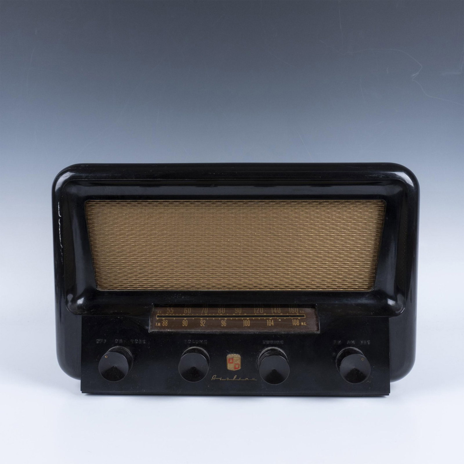Montgomery Ward Airline Radio: A sleek black radio with a striking gold speaker and four elegant tuning knobs for precise control. Montgomery Ward marked. Airline marked. Dimensions: 14.25"L x 8"W x 9.25"H Manufacturer: Montgomery 
