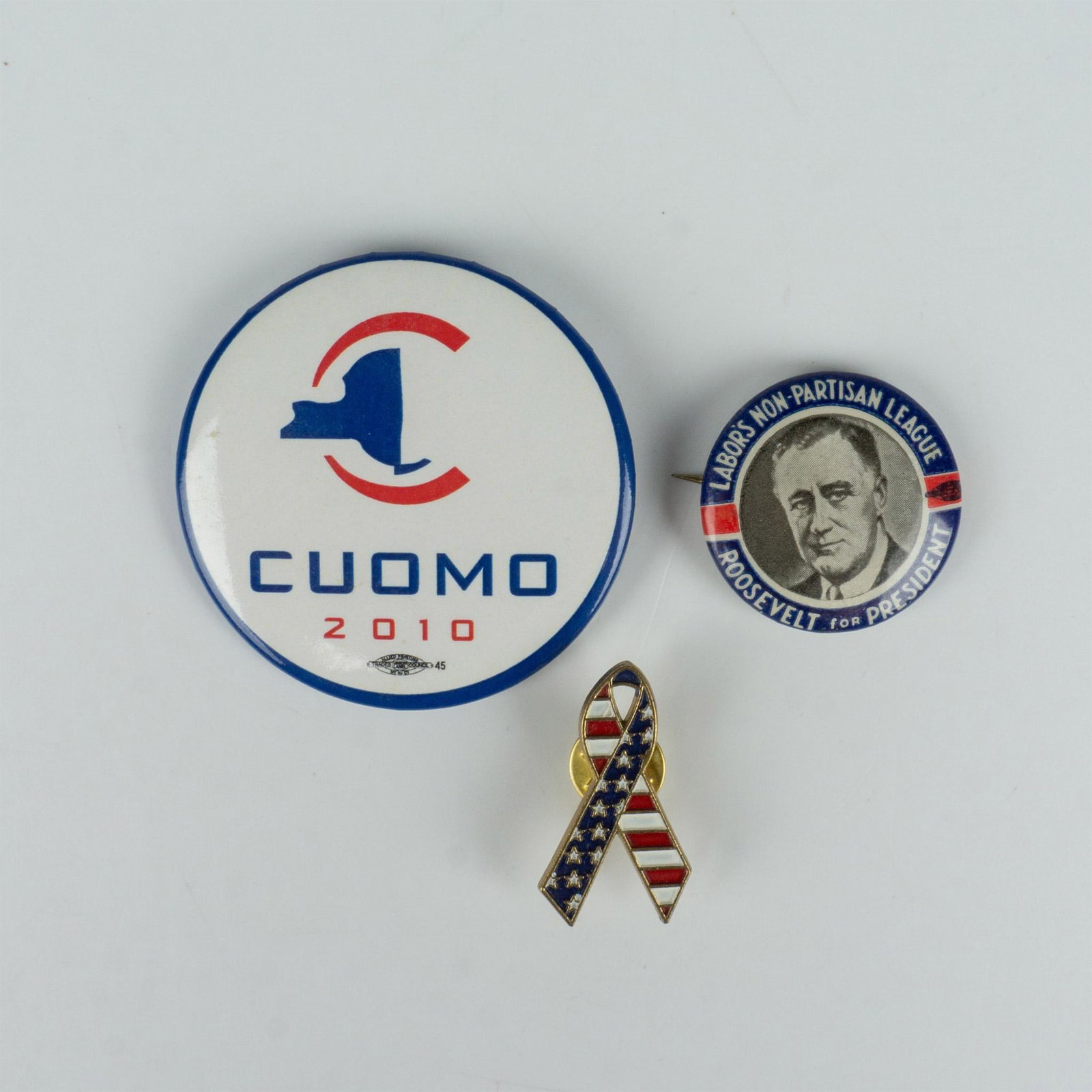3pc United States Political Pins, Roosevelt, Cuomo, and Flag: This set of three pins includes an election pin featuring Roosevelt's photo and the text Labors Non-Partisan League, an election pin for Cuomo 2010 with an outline of New York, and a patriotic America
