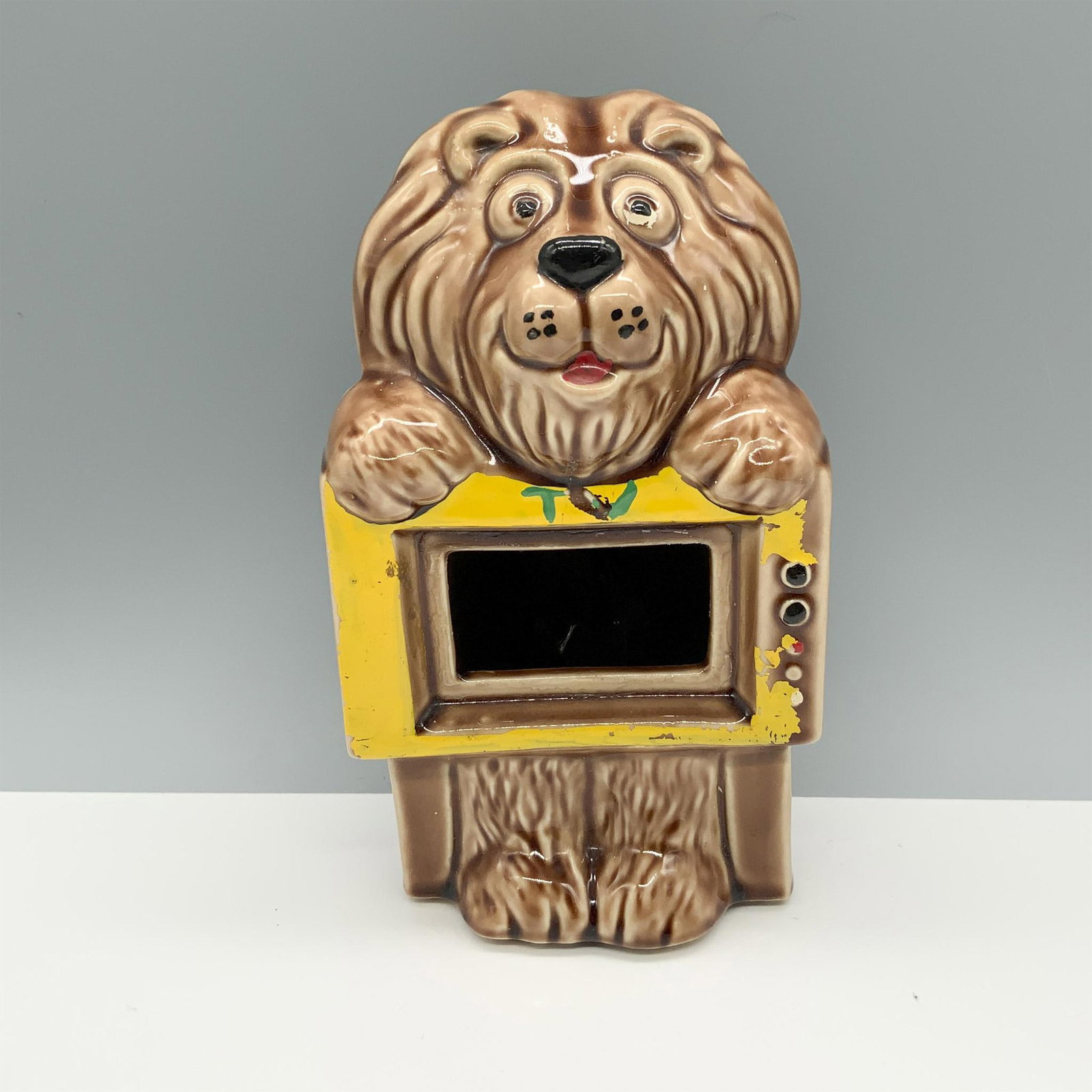 McCoy Pottery Lion TV Coin Bank: Adorable container used to hold currency or small items that depicts an animal leaning over a television. McCoy backstamp on base. Issued: 20th century Dimensions: 5.25"L x 4.75"W x 8.75"H Manufacture