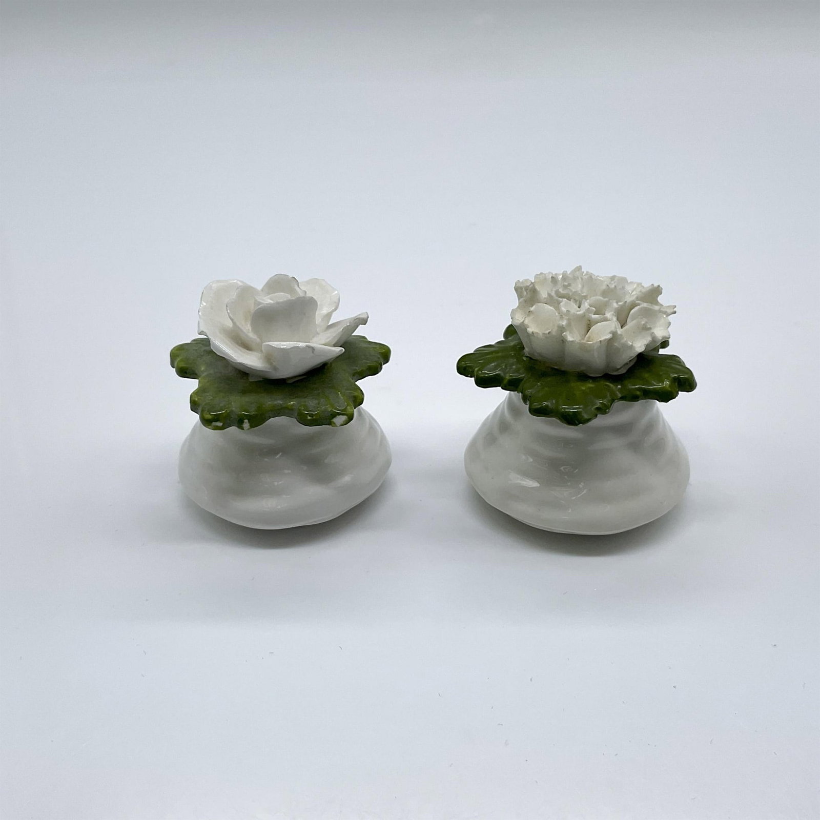 Pair of Aynsley English Fine Bone China Shakers: A set of 2 small white and green porcelain salt and pepper shakers, formed as flowers. Aynsley marked. Approximate measurement for a shaker: 1.75"W x 1.5"H. Issued: 20th century Dimensions: See Descri