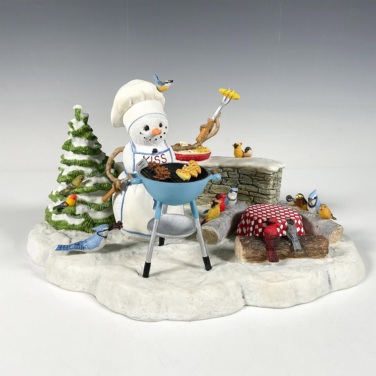 Lenox by Lynn Bywaters Figurine: Hand painted resin with different textures of a small winter-themed figure featuring a snowman grilling in the snow, with a group of birds gathered around. This item has its original box. Box measures