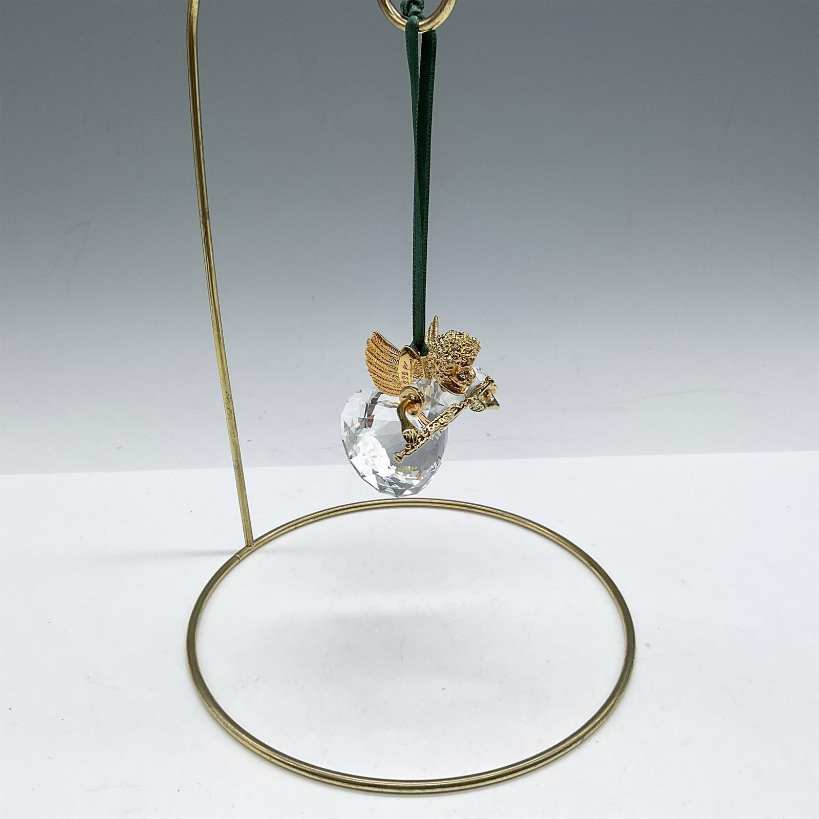 Swarovski Crystal Memories, Angel Ornament with Flute: Limited edition series of Angels for the Christmas Memories series. Designed with gilded head, wings, arms and legs wearing a faceted crystal dress playing a flute. Green satin ribbon provided for han