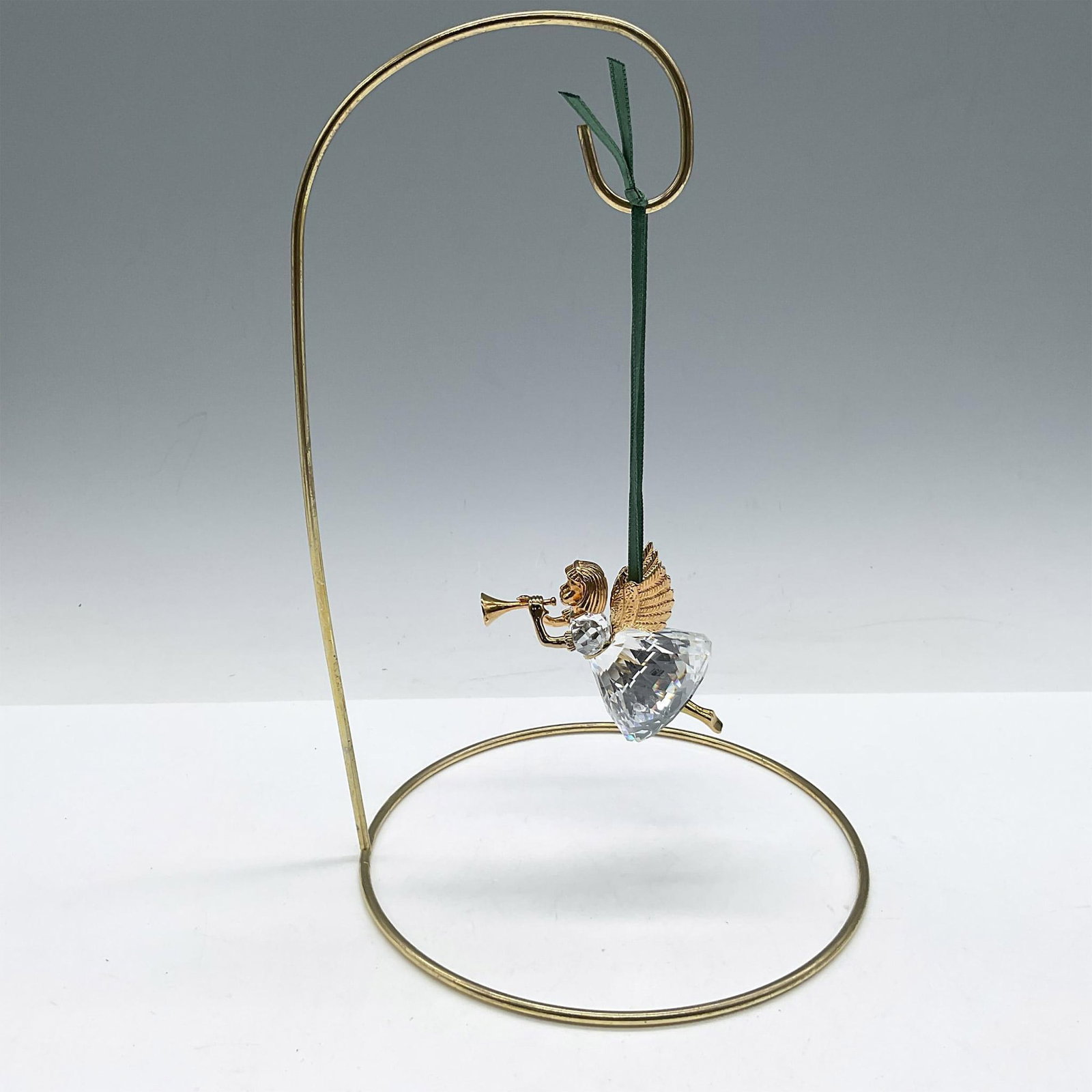Swarovski Christmas Memories Ornament, Angel with Horn: Limited edition series of Angels for the Christmas Memories series. Designed with gilded head, wings, arms and legs wearing a faceted crystal dress blowing a gilded horn. Green satin ribbon provided f