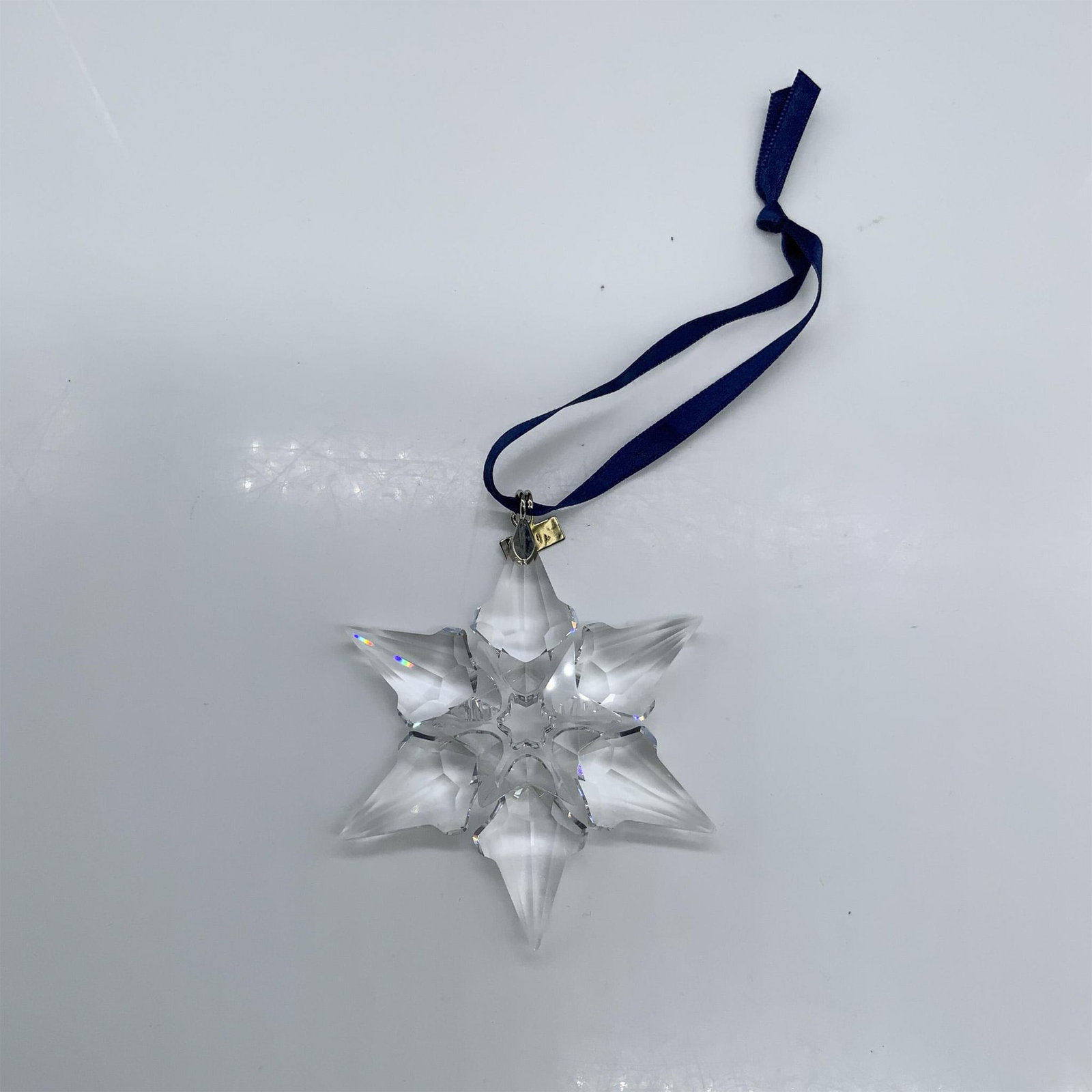 Swarovski Crystal 2000 Christmas Ornament 243452: This beautiful Christmas ornament was crafted from faceted clear crystal with silver metal and a blue ribbon. Swarovski hallmark. The triangular box measures 5.75"L x 6.5"W x 1.25"H. Artist: Heinz Tab