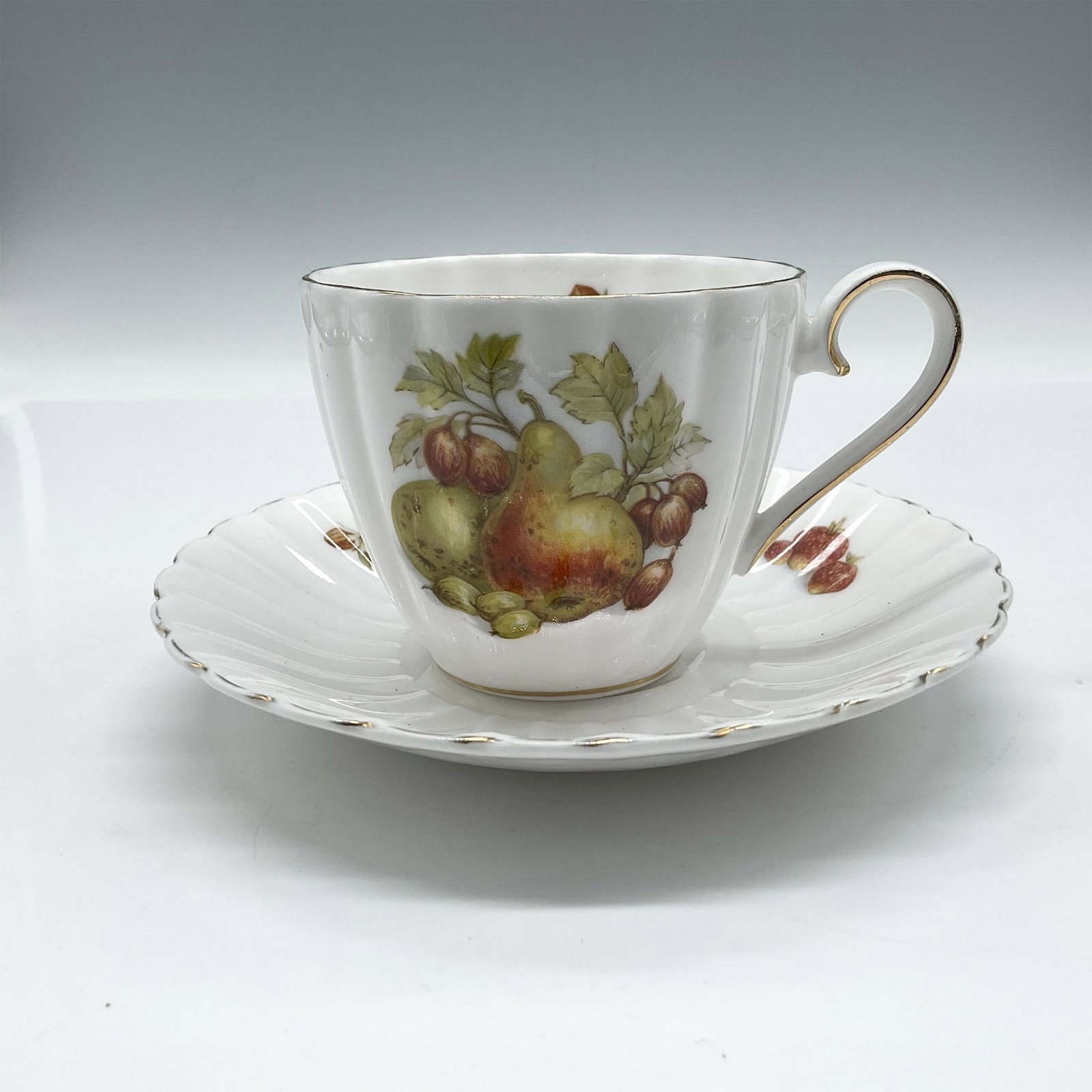 2pc Royal Tuscan Bone China Cup & Saucer Set, D2933: Pleated Bone China with fruit design of pears and strawberries. Gilt accent added to rim, base and handle. Cup measures 2.75"H x 3.25" dia. and saucer 1"H x 5.5" dia. Royal Tuscan England backstamp. I