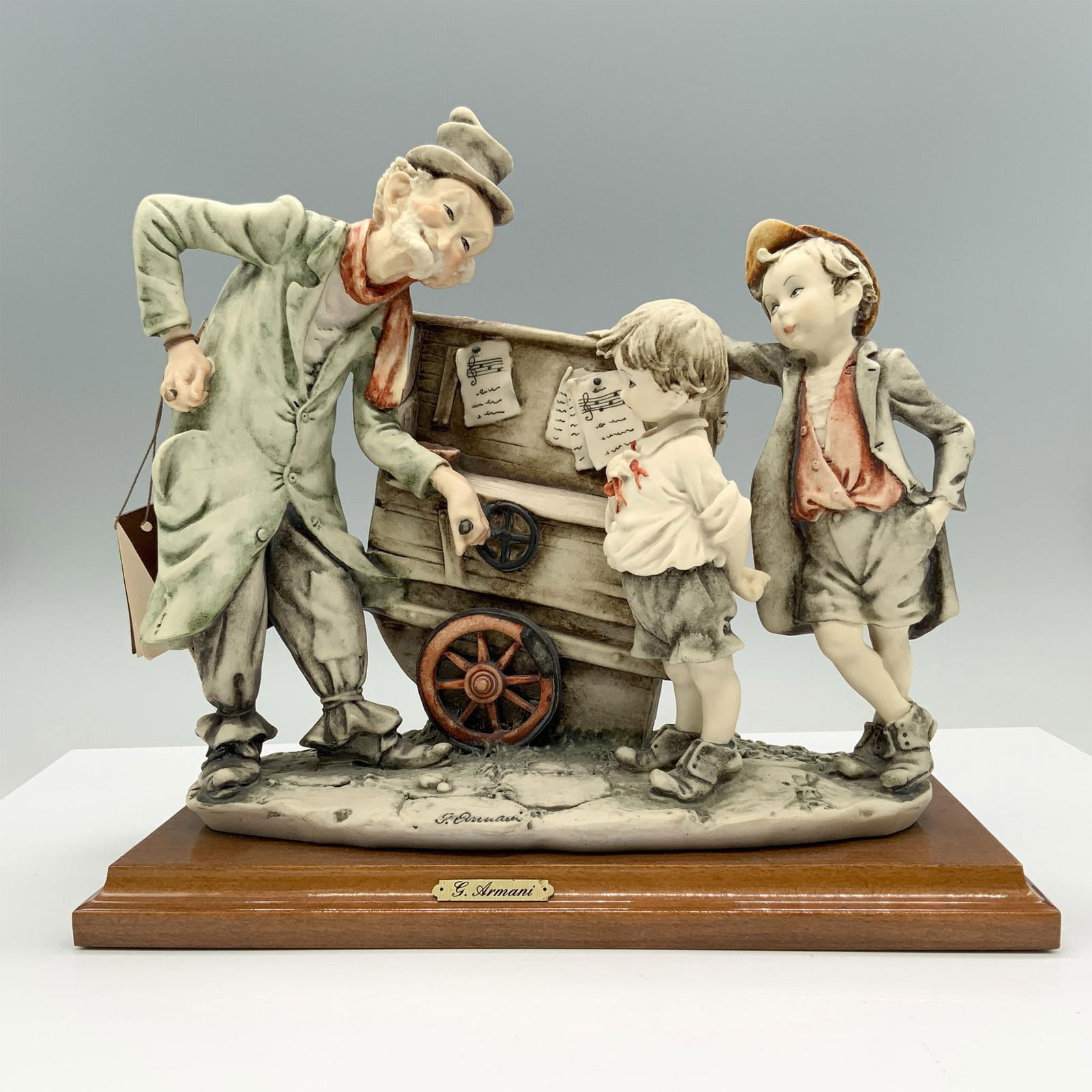 Florence Giuseppe Armani Figurine, Organ Grinder: Fine crafted resin captures a charming scene of an elderly street organ player interacting with two curious children. Marked made in Italy. Impress artist signature. Attached to wooden base. Capodimon