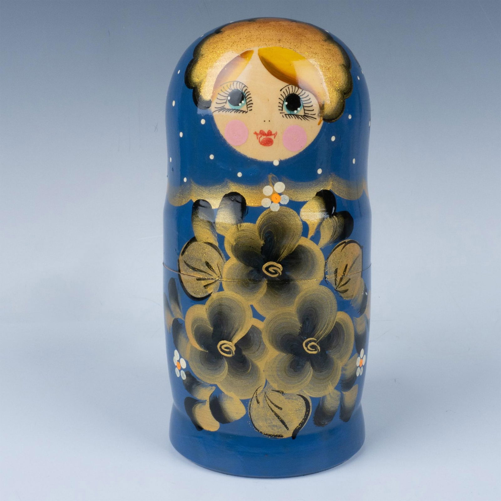 Russian Matryoshka Nesting Doll: Beautifully handmade and hand-painted set of seven nested multicolored dolls, featuring humorous smiling faces, primarily painted in a night sea blue with gold and black floral patterns. Dimensions: 4