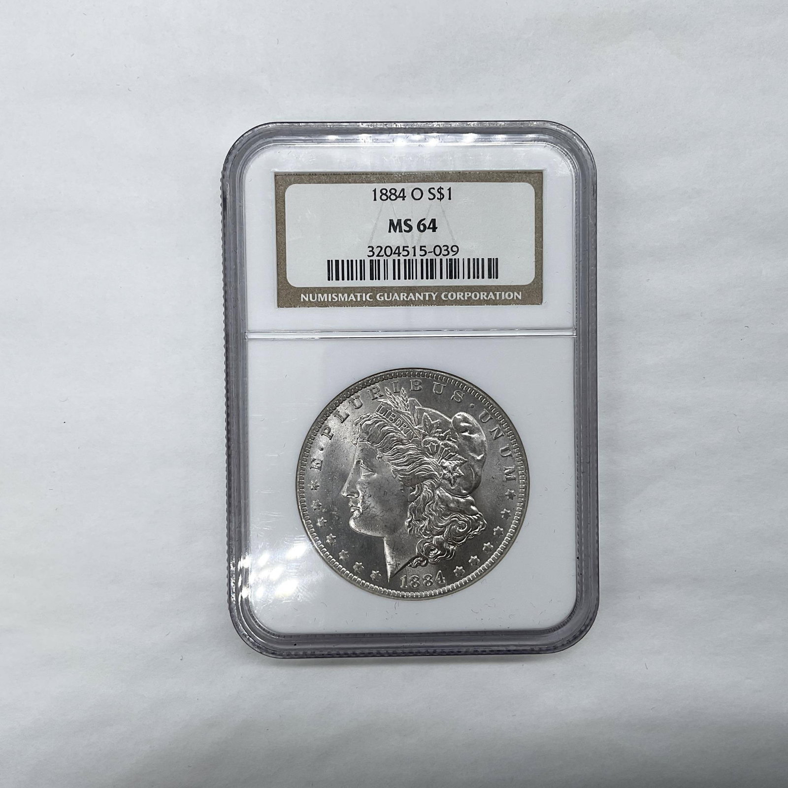 1884-O Morgan Silver Dollar NGC Graded MS64: New Orleans Mint. The obverse side features Liberty in profile. She is shown in cap, flora, and crown. The reverse side depicts an eagle with outstretched wings gripping arrows and an olive branch. Th