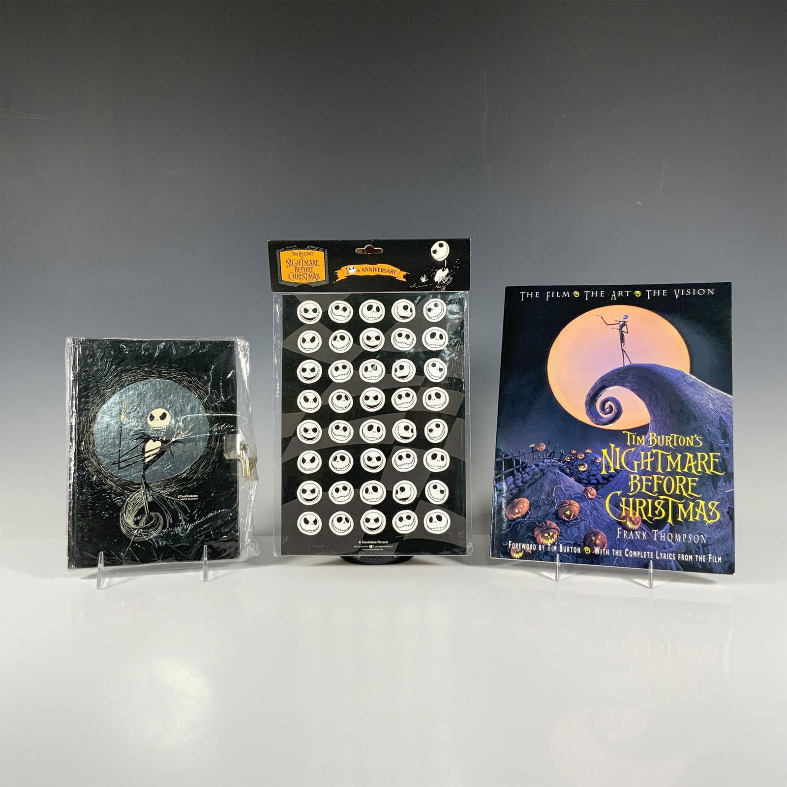 3pc Nightmare Before Christmas Merch: Includes a sealed set of 10th anniversary stickers, a sealed lockable journal with Halloween Jack on the cover and Christmas Jack with Sally on the reverse, and an art and lyric softcover book celebra