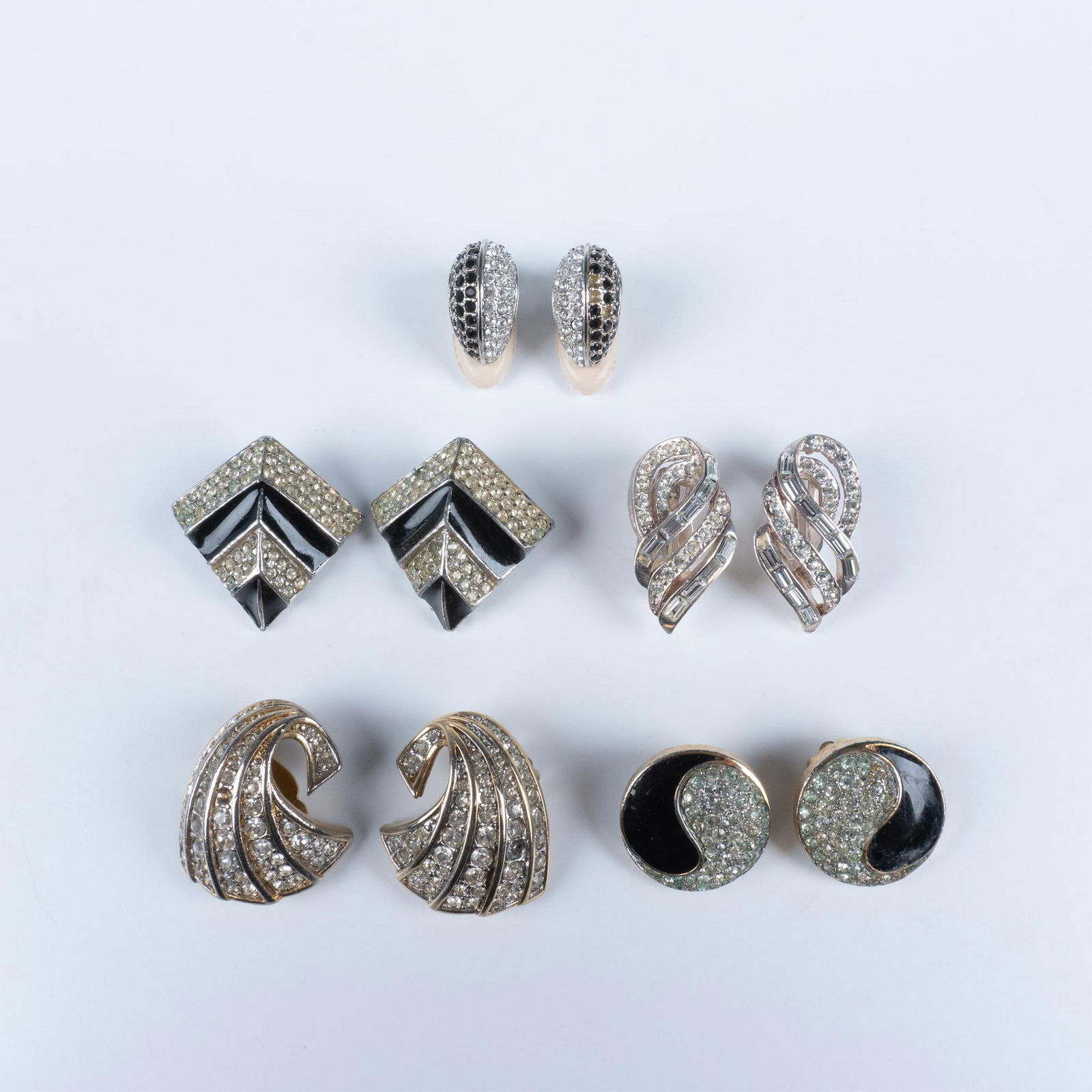5 Pairs of Designer Paved Clip On Earrings, Signed: Gorgeous group of silver and gold toned, decorated with incrusted rhinestones and black enamel. Largest piece dimensions: 1.25''L x 1''W, Each. Marked Nina Ricci, Joseph Mazer Adolfo for Mazer, Swarov