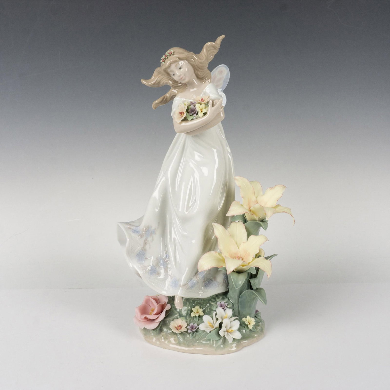 Mystical Garden 1006686 - Lladro Porcelain Figurine: Glossy limited-edition figure is 980 of 5000. Young woman is holding flowers, standing in a garden of flowers. Lladro backstamp. This item has its original box: 9"L x 13.5"W x 8"H. Artist: Jose Javier