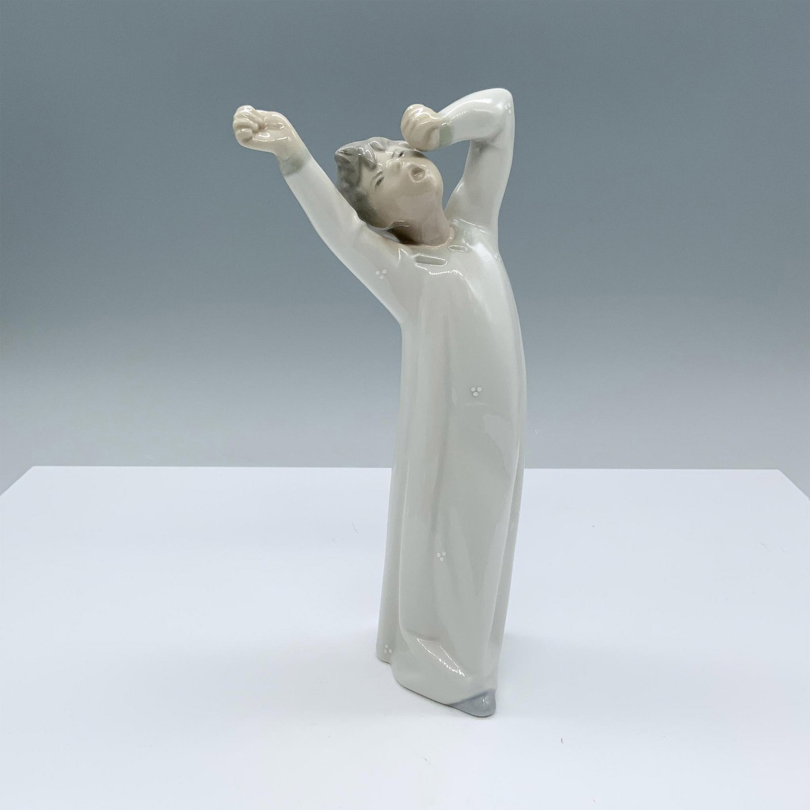 Boy Yawning 1004870 - Lladro Porcelain Figurine: Glossy finish; Lladro backstamp. Artist: Fulgencio Garcia Issued: 1974-1999 Dimensions: 4"L x 2.75"W x 8.5"H Manufacturer: Lladro Country of Origin: Spain