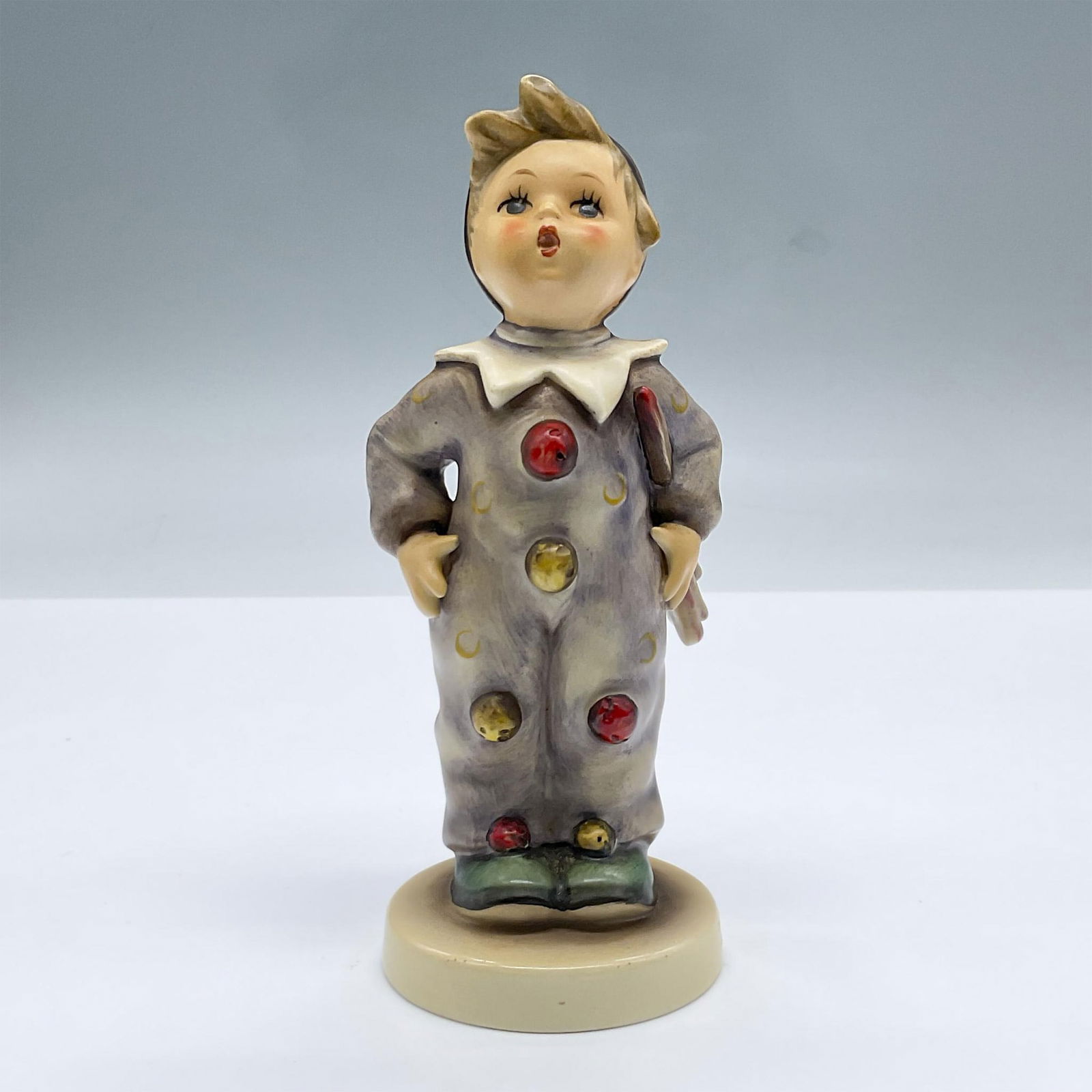 Goebel Hummel Porcelain Figurine, Carnival 328: A figure of a boy in a clown suit. Goebel Hummel backstamp. Issued: 20th century Dimensions: 2.5"L x 2.25"W x 6"H Manufacturer: Goebel Hummel Country of Origin: Germany