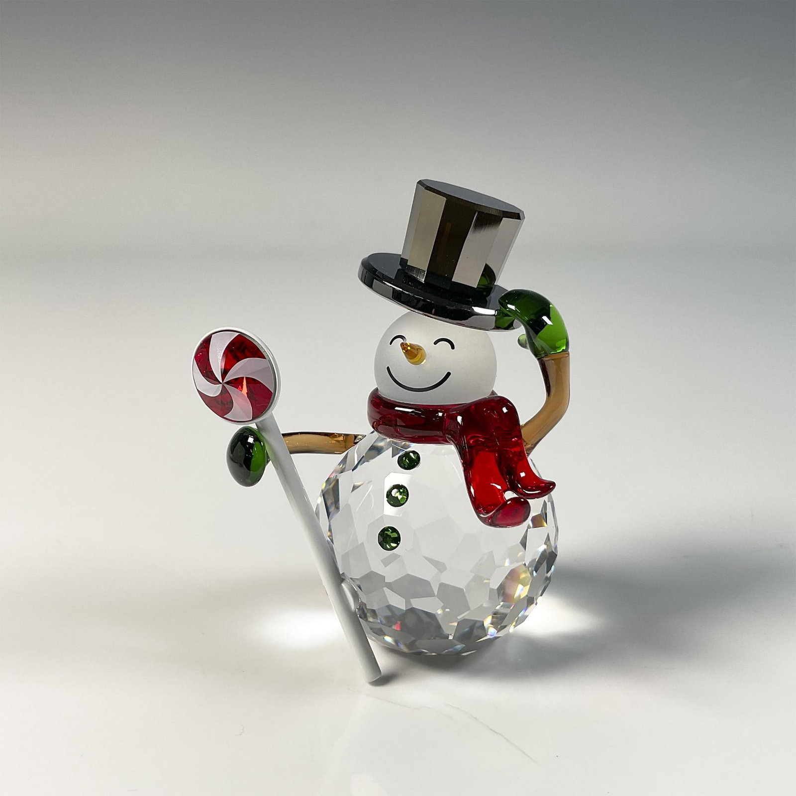 Swarovski Crystal Figurine, Dulcis Snowman: Delightful Christmas snowman figure, crafted from clear crystal with red and green accents. Swarovski swan mark. This item includes original box: 5"L x 3.25"W x 5"H. 5655434. Artist: Michele Blasilli 