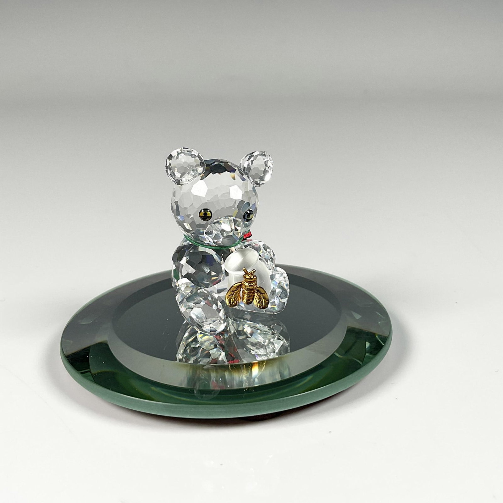 Swarovski Crystal Figurine and Base, Kris Bear, Honey Pot: Figure from When We Were Young theme, featuring a bear cherishing its honey pot adorned with an attached golden colored bee for an adorable accent. Swarovski swan mark. This item includes a mirror bas