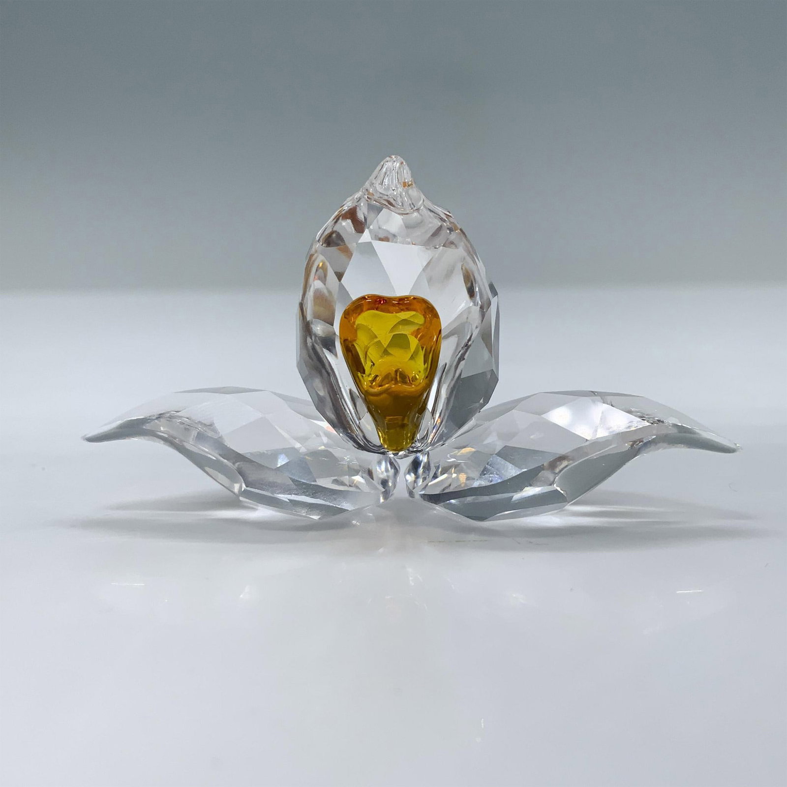 Swarovski Crystal Figurine, 2018 Gift African Orchid: Beautiful crystal clear flower with faceted petal and leaves, featuring a bright orange center. SCS membership renewal gift. Swarovski swan mark. This item has its original box. Box measures: 3.75"L x