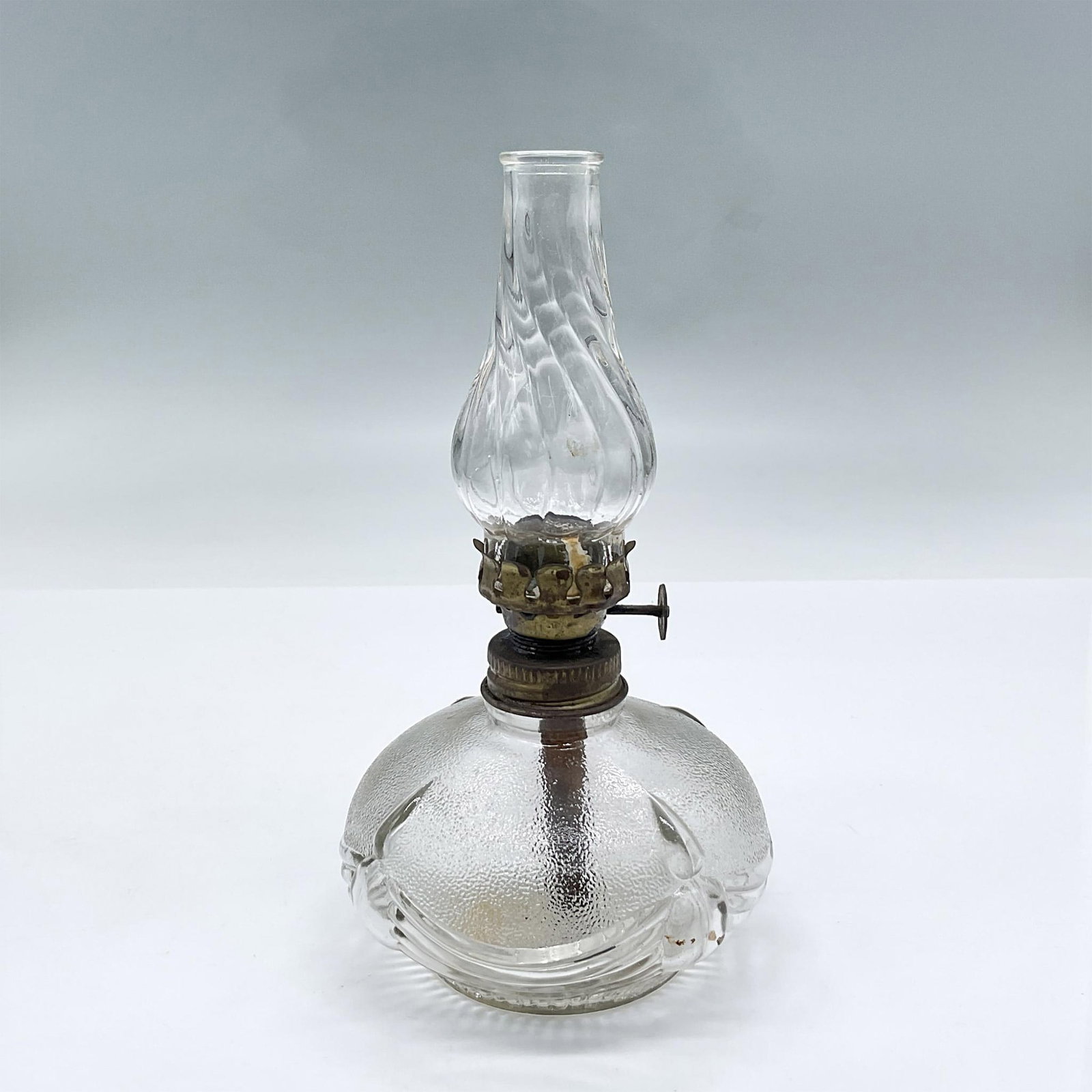 Vintage Clear Glass Oil Lamp: Clear and textured glass oil lamp including chimney with ribboned sash design on the body Dimensions: 6.5"H x 3.75" dia