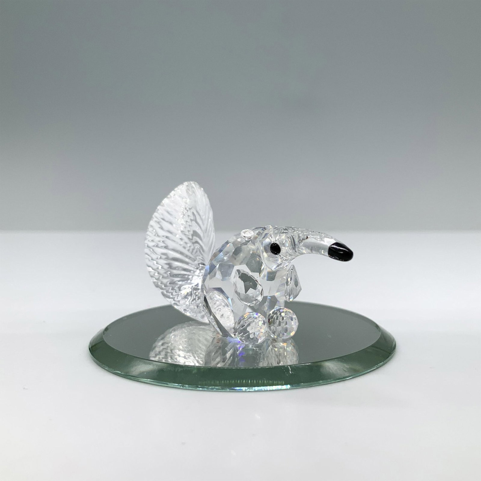 Swarovski Crystal Figurine, Anteater: Miniature anteater made in clear crystal, its body is faceted, and the tail is molded. This item has its original box. Box measures: 2.5"H x 3.25" dia. Swarovski swan mark. 271460. Certificate of Auth