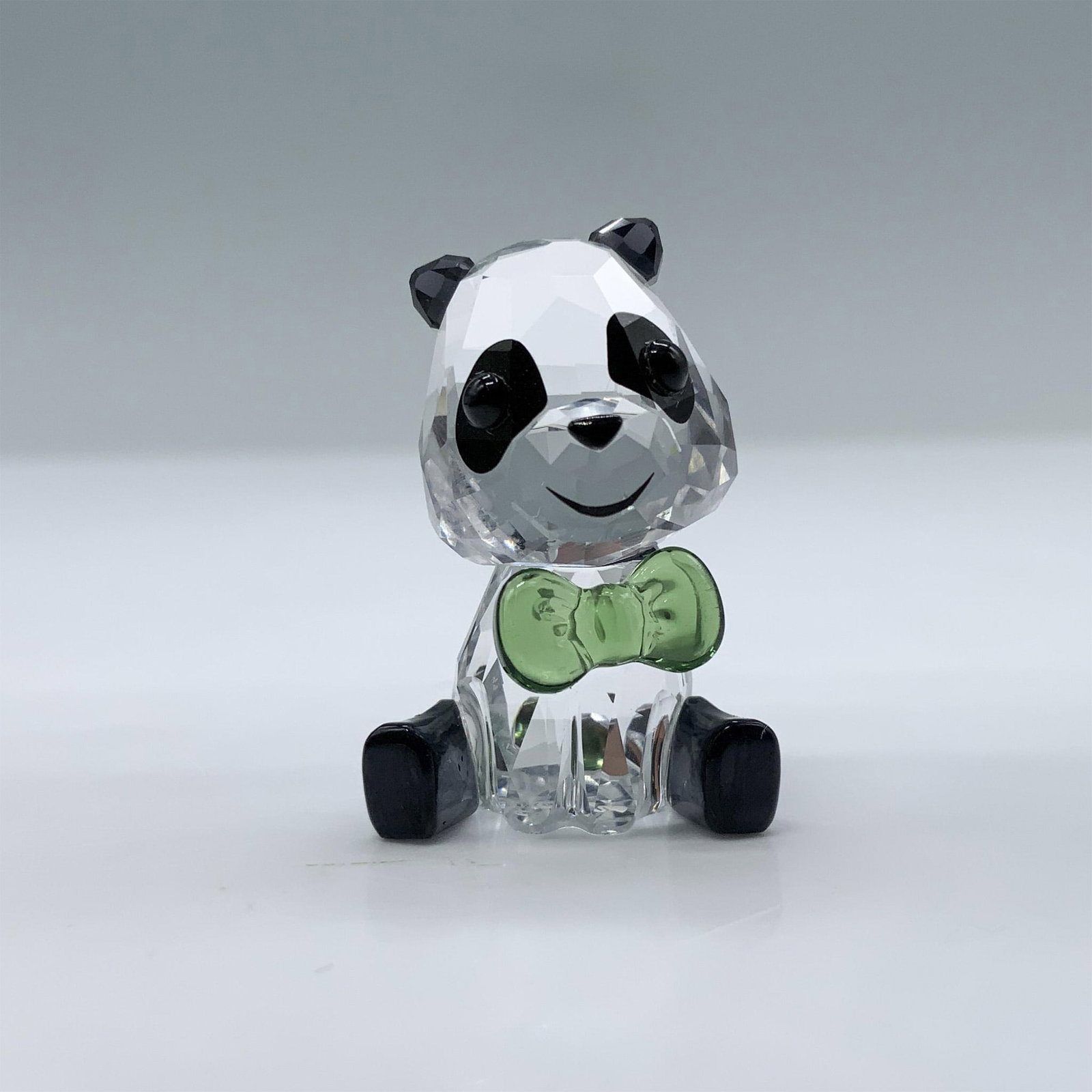 Swarovski Crystal Figurine, Plushy the Panda: Adorable miniature of a panda with clear, black and green crystal. This item has its original box. Box measures: 3.75"H x 3.25" dia. Swarovski swan mark. 5619234. Artist: Heinz Tabertshofer Issued: 20