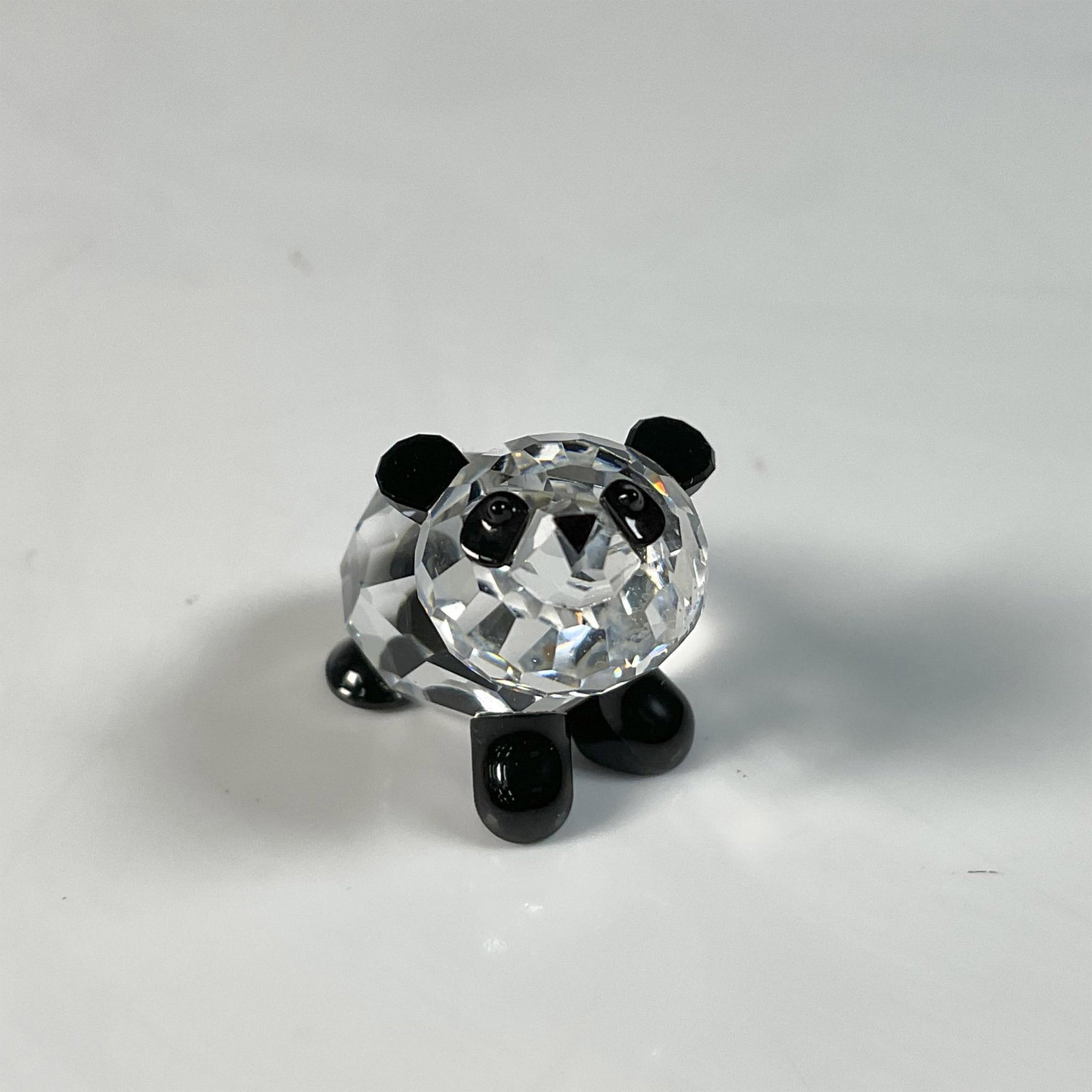 Swarovski Crystal Figurine, Panda Baby: Adorable baby panda figure in a playful pose trying to stand somehow, with black accents on its ears, eyes, and legs. Swarovski swan mark. This item includes an original box: 3.25"W x 2.5"H. 181081. A