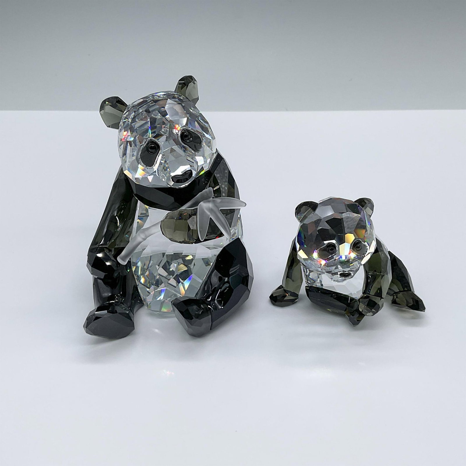 Pair of Swarovski Crystal Figurines, Panda Mother and Cub: SCS first edition of the Endangered Wildlife trilogy. The collection has a mother panda and her cub in back and clear crystal. The mother is depicted holding a stalk of bamboo. Marked Swarovski swan H